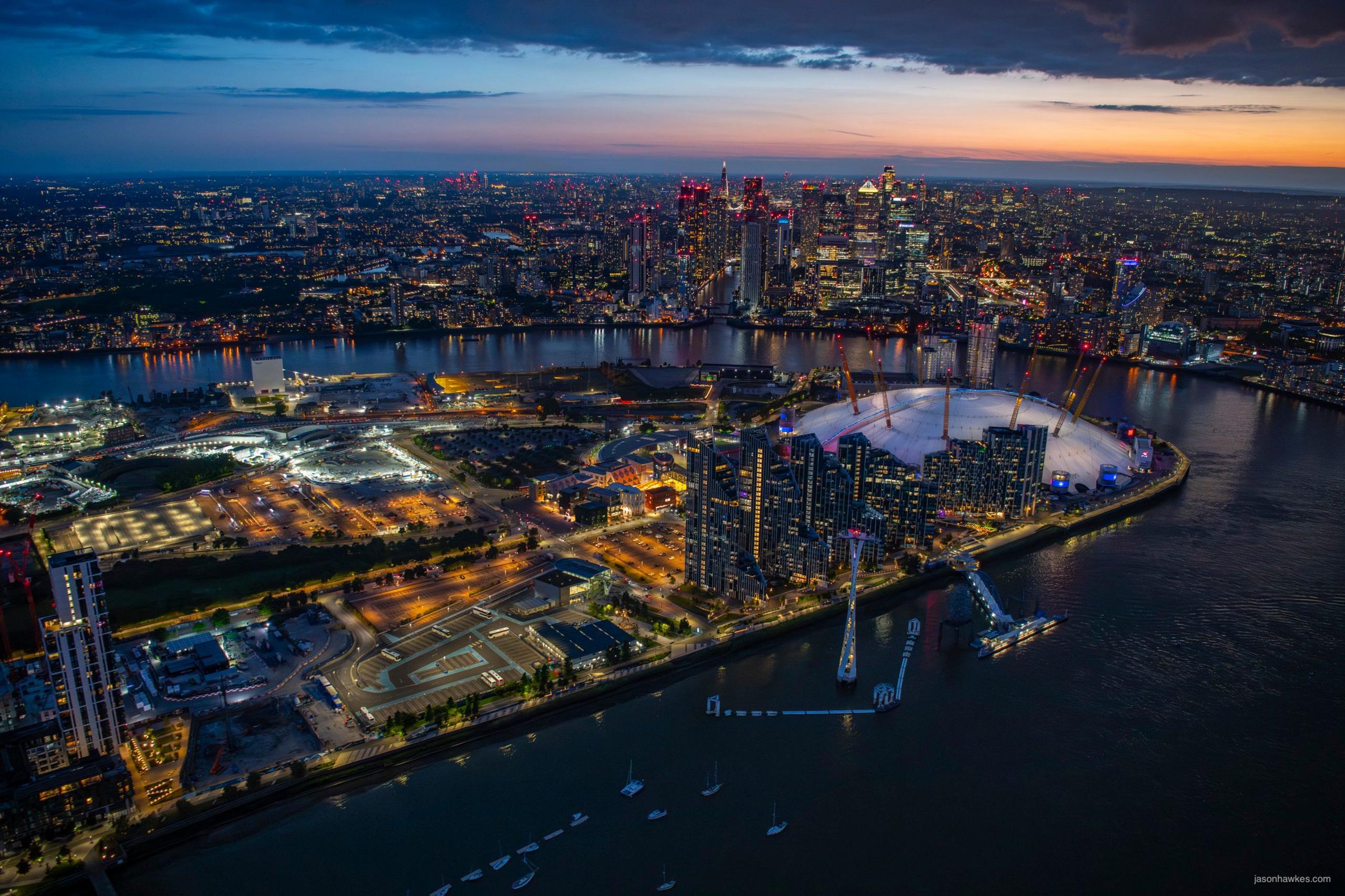 Darkness descends over the bend in the River Thames, showing O2 in foreground and City of London in background