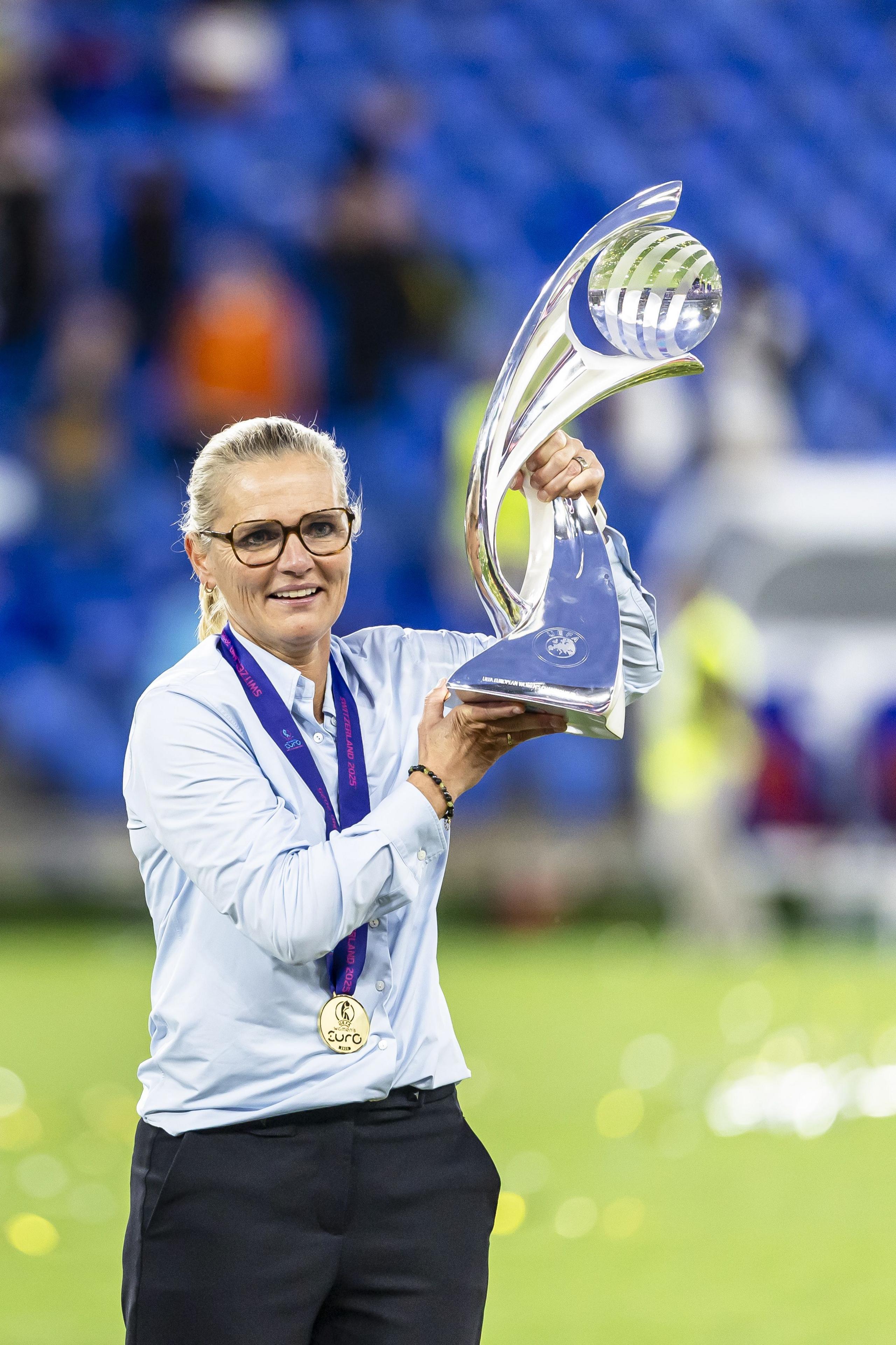 sarina wiegman smiling while holding the trophy in the stadium