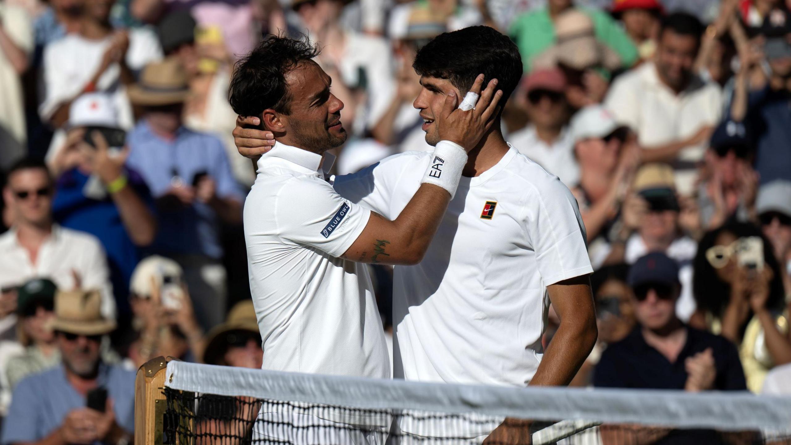 Fabio Fognini and Carlos Alcaraz embrace at the net after their Wimbledon match