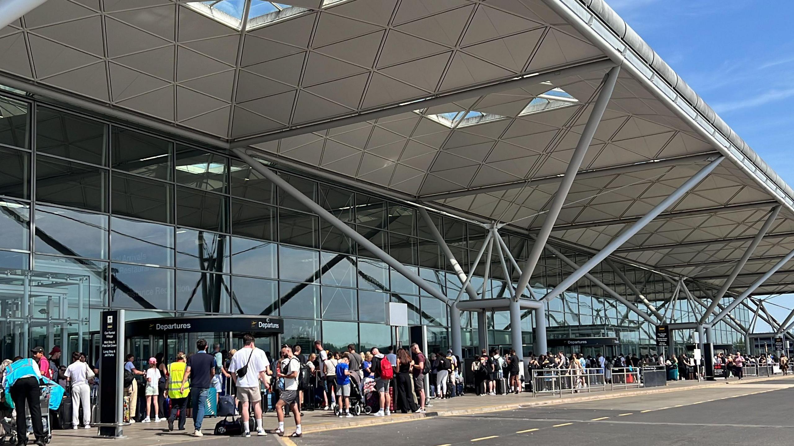 People queueing along the outside of the Stansted terminal in July 2024 after a IT outage 