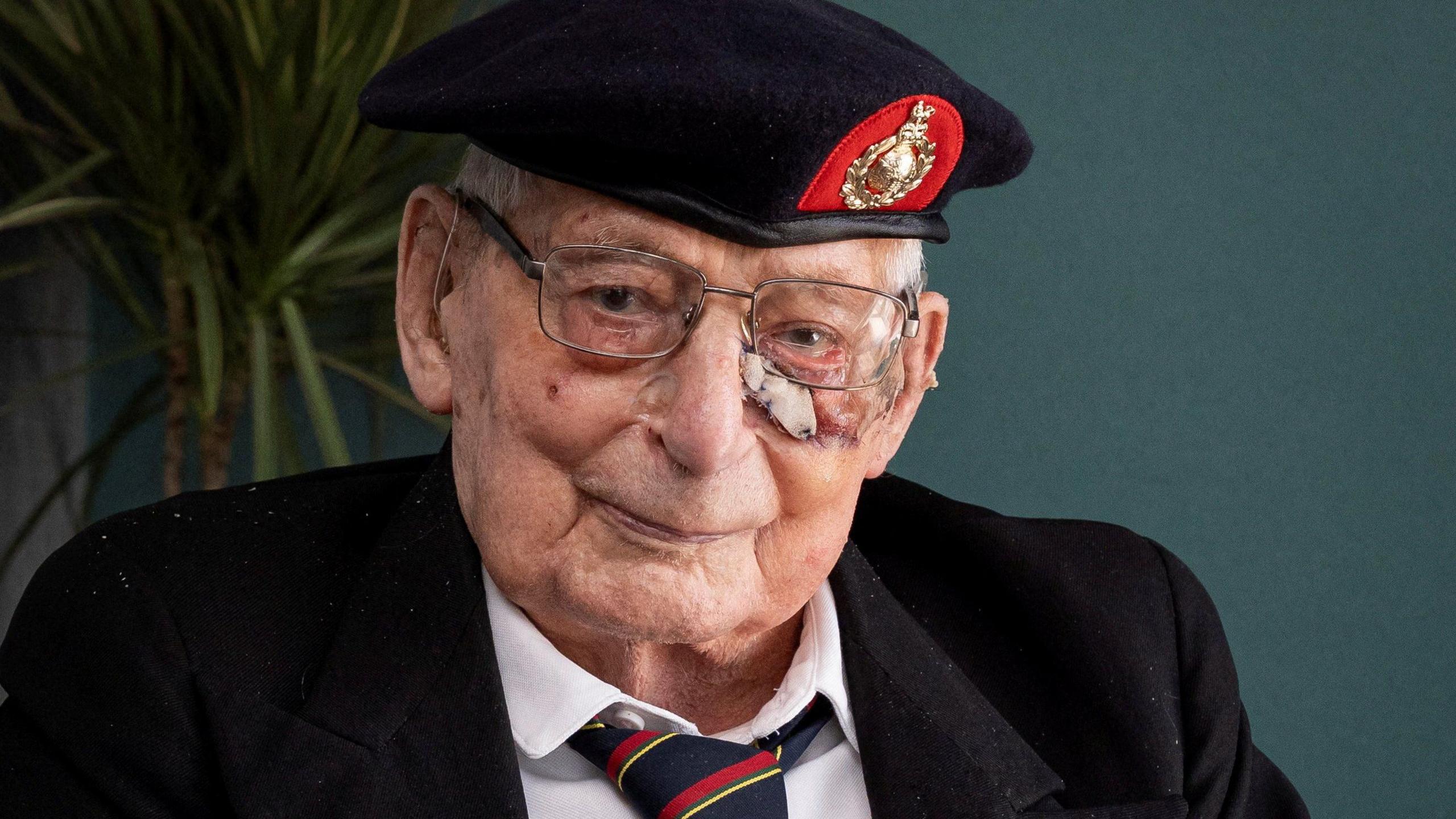 James "Jim" Wren. He is an elderly man with white short hair. He is wearing a Royal Navy hat, reading glasses, a white shirt, black blazer and a red, black and gold striped tie. He is smiling.
