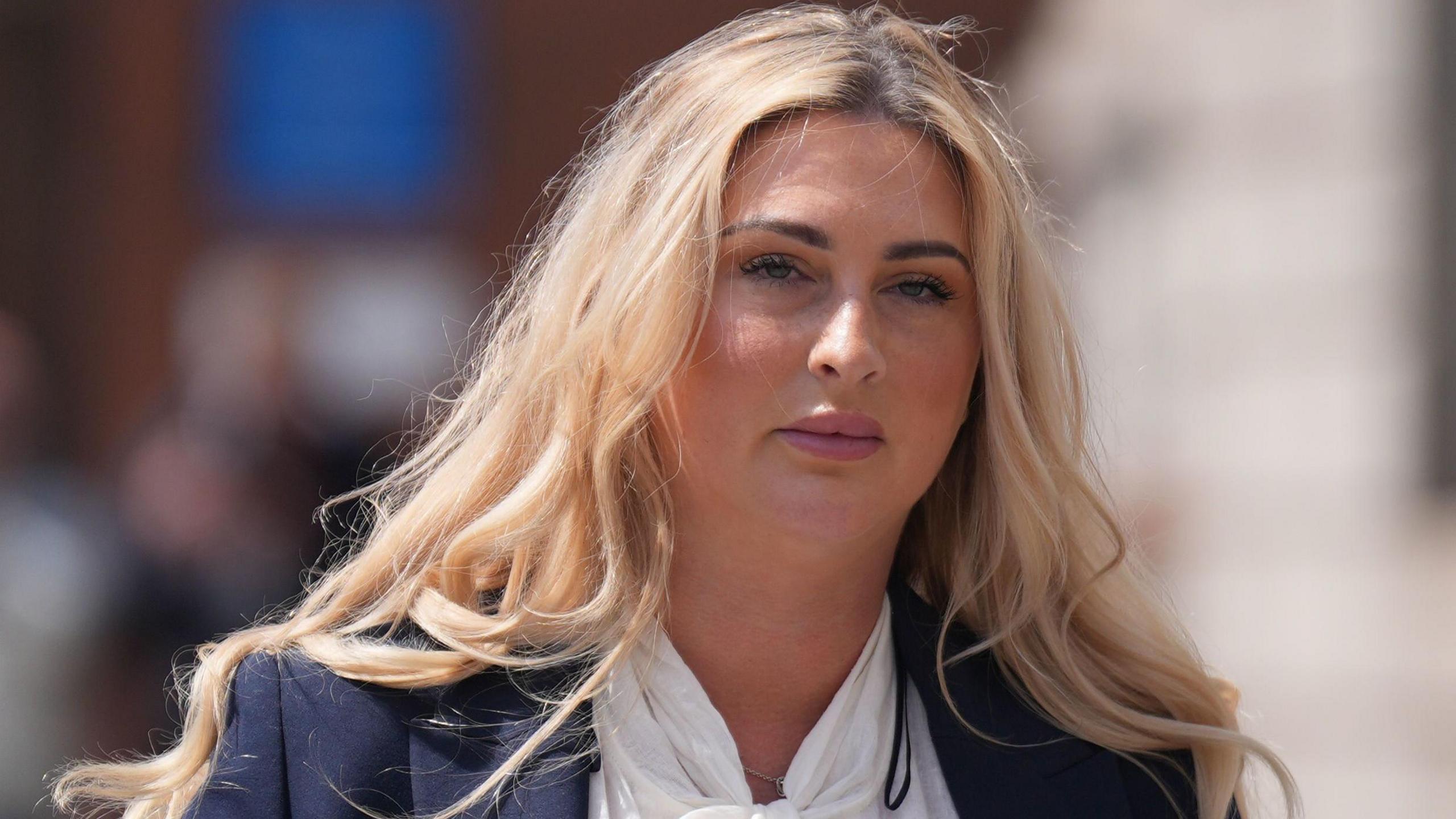 Nikita Hand with blonde hair. She is wearing a navy blazer and white top.