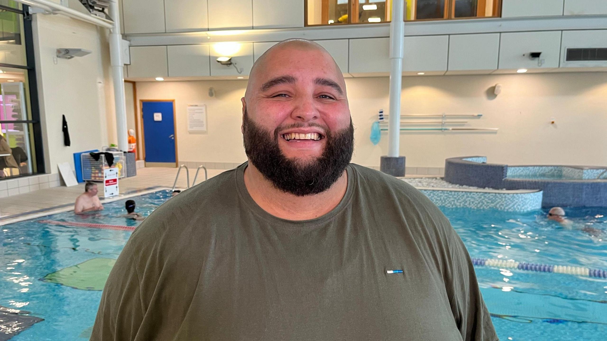 Adam Lopez in a t-shirt with the swimming pool behind him