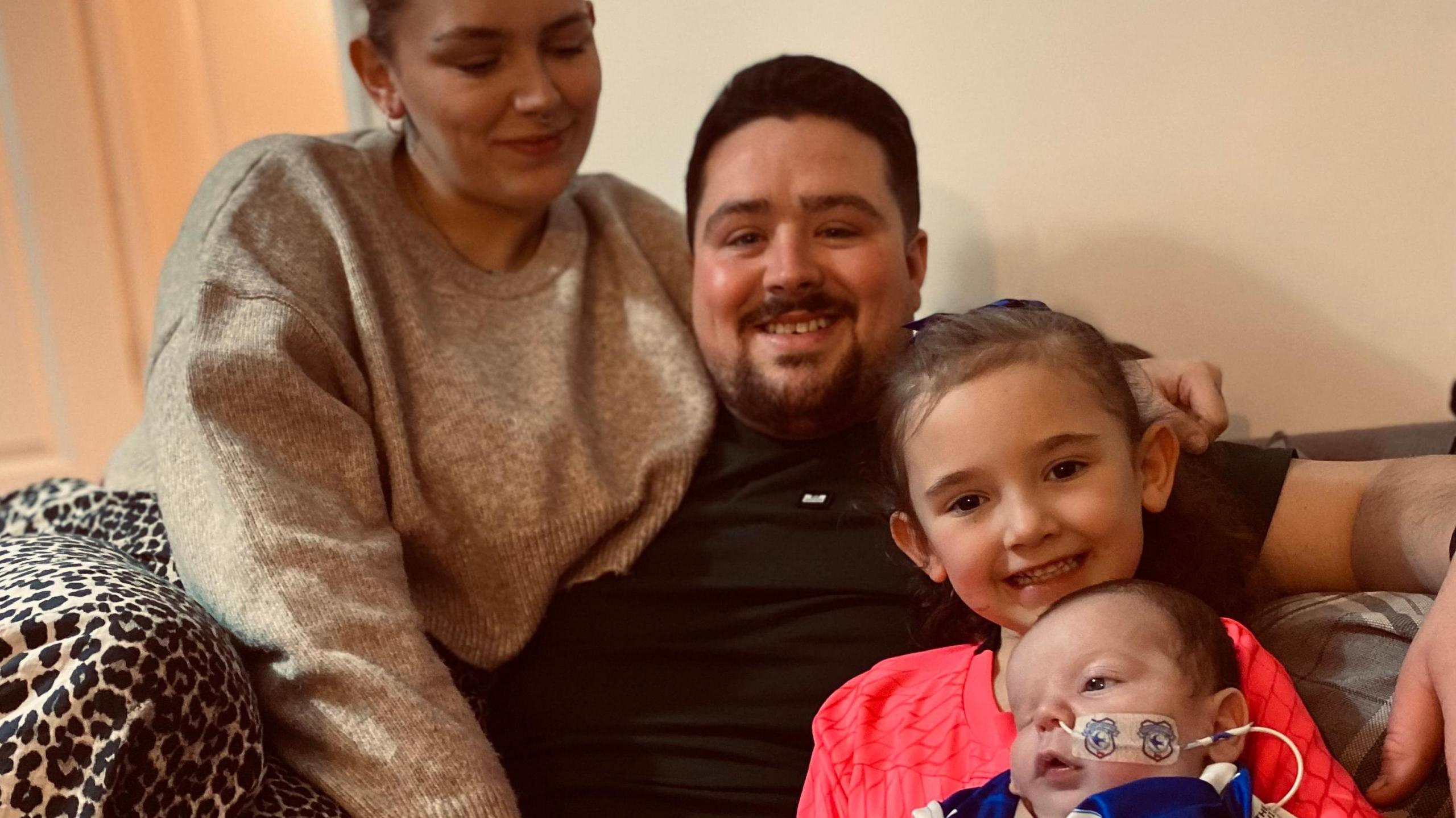 Grace and Rhys are pictured here with their daughter Myah and their son Vinnie. The family is pictured smiling in their livingroom.