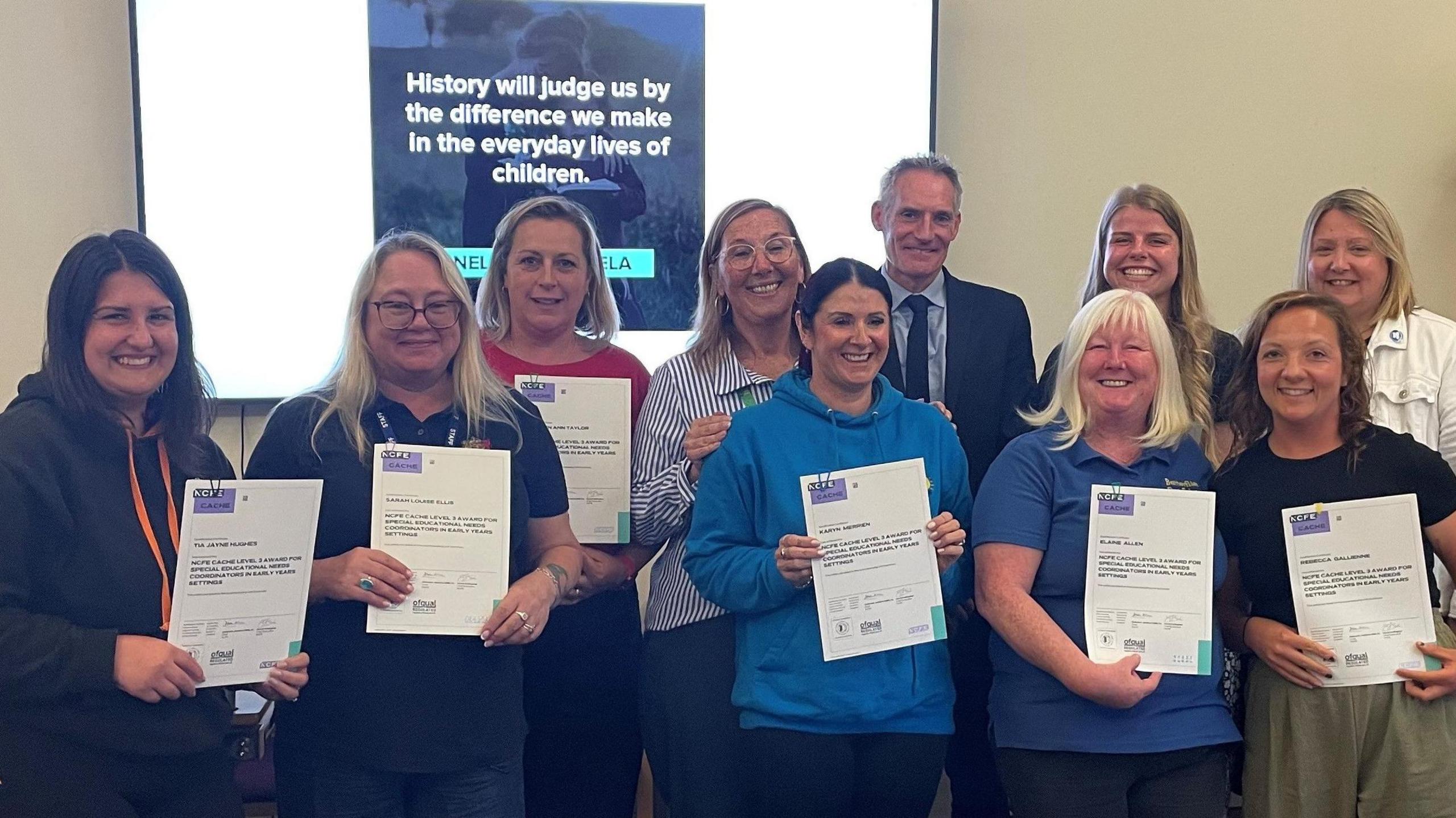 Nine women and one man are smiling, with six women holding up certificates.
