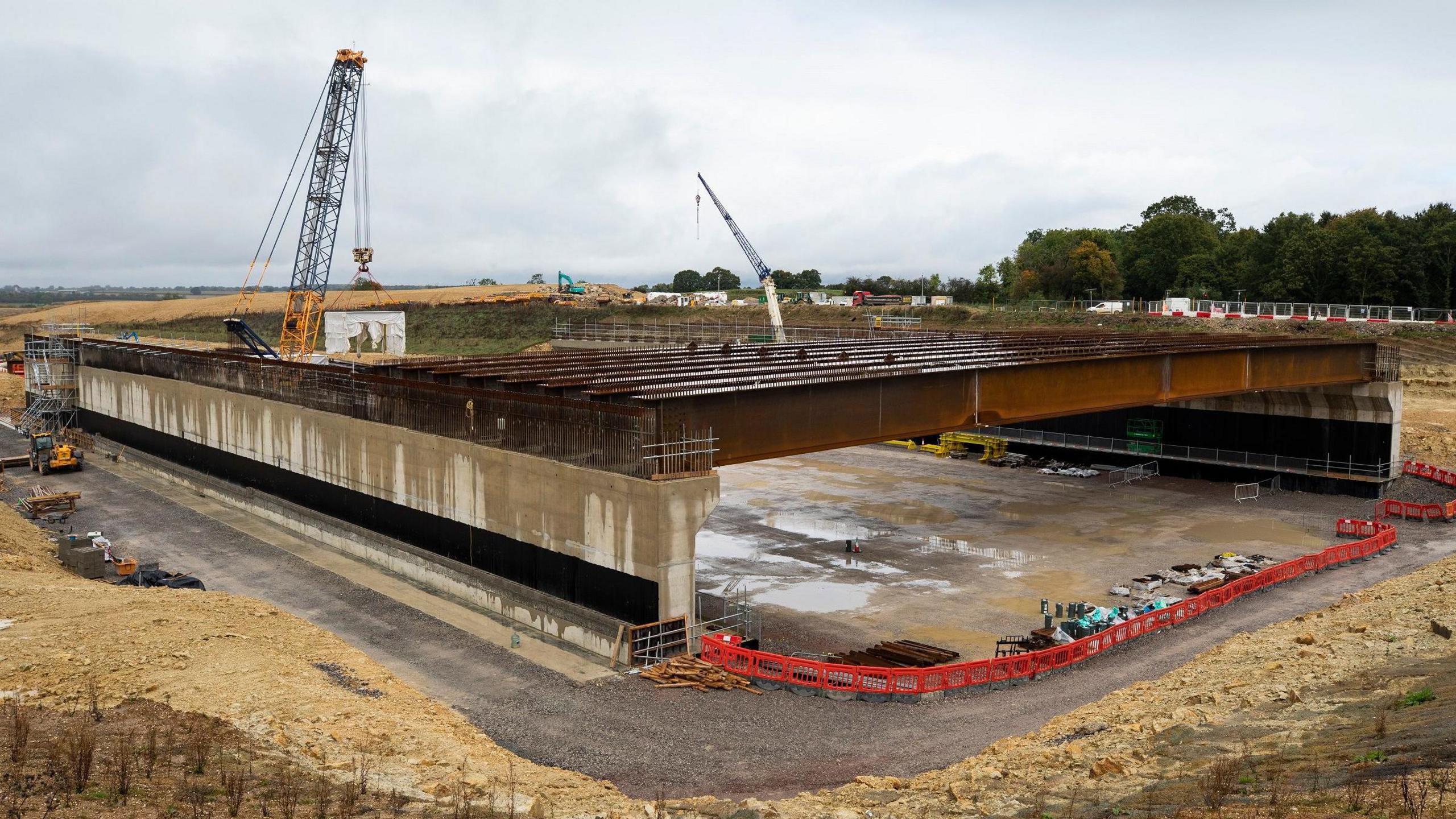 A building site with a wet sand floor, grey concrete bricks and steel beams creating a bridge 