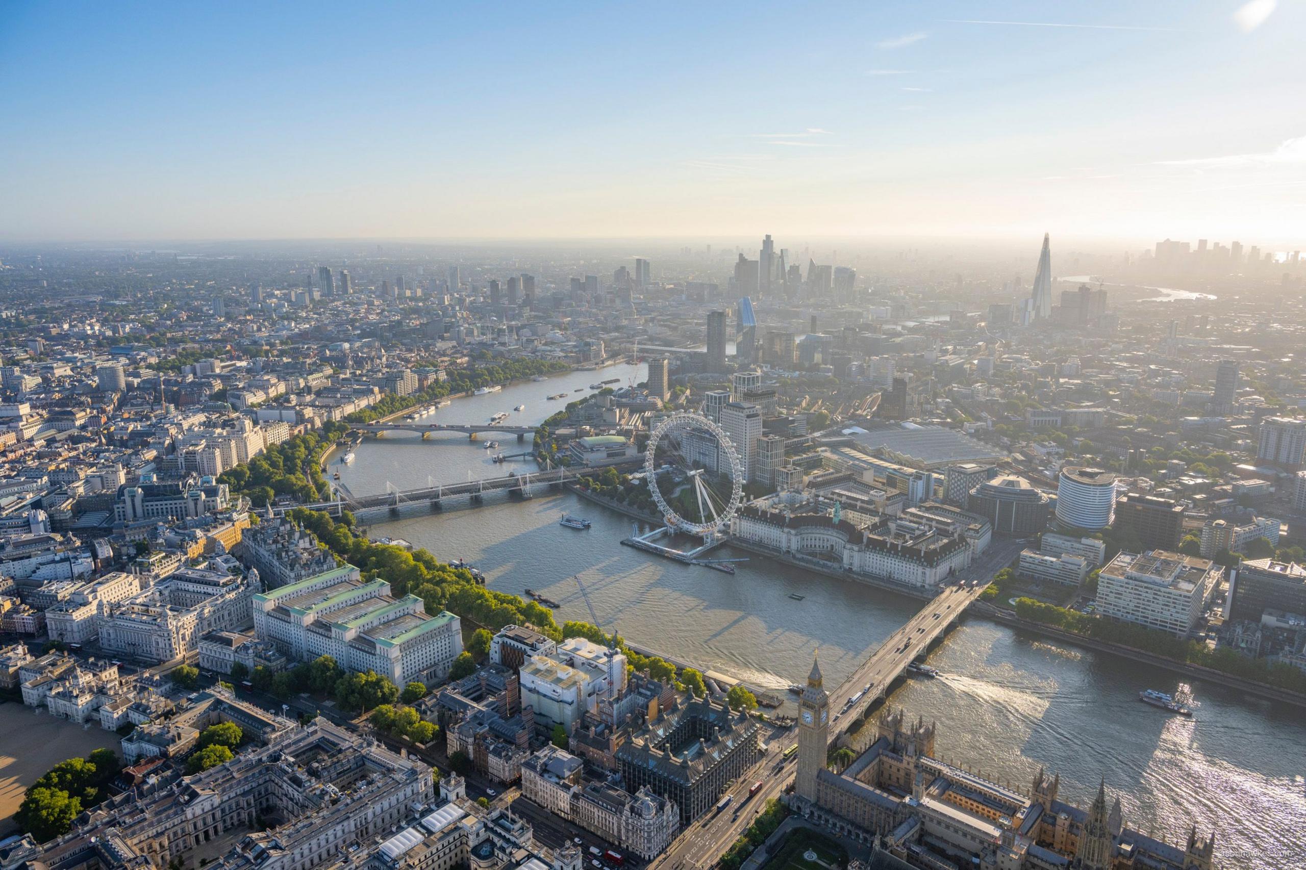 Sun shines over River Thames, showing London Eye in foreground and Shard and City of London in background