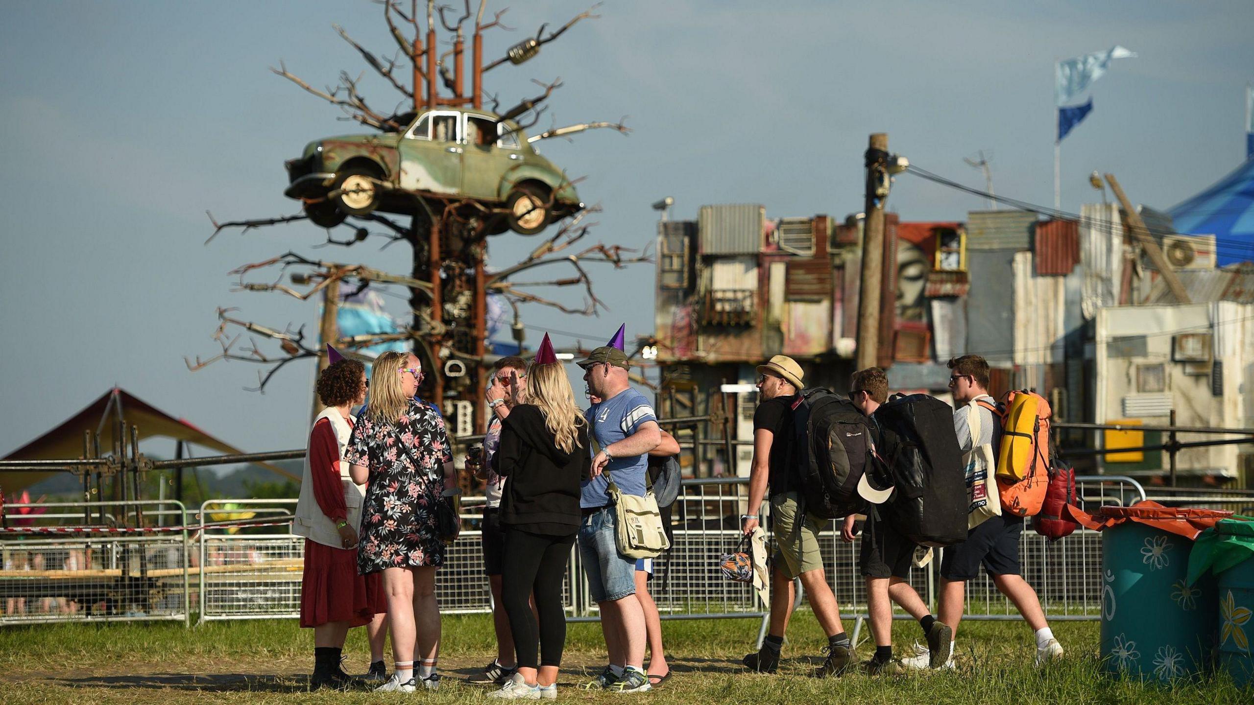 Crowd stood in front of car sculpture 