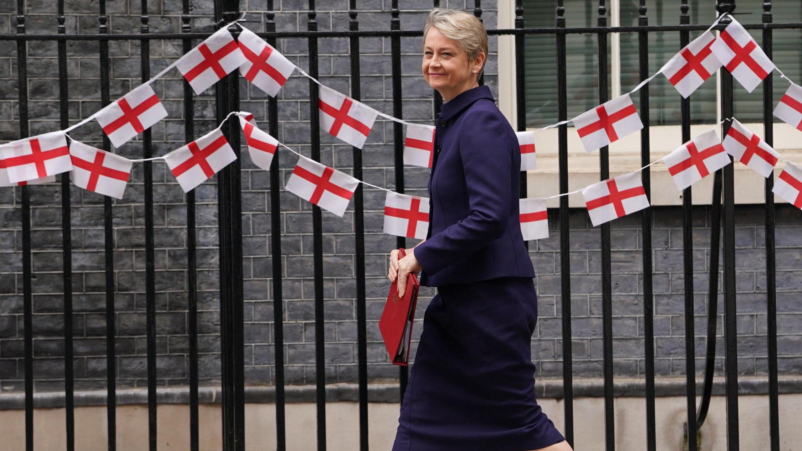 Home Secretary Yvette Cooper arrives at Downing Street in front of a row of English flags 