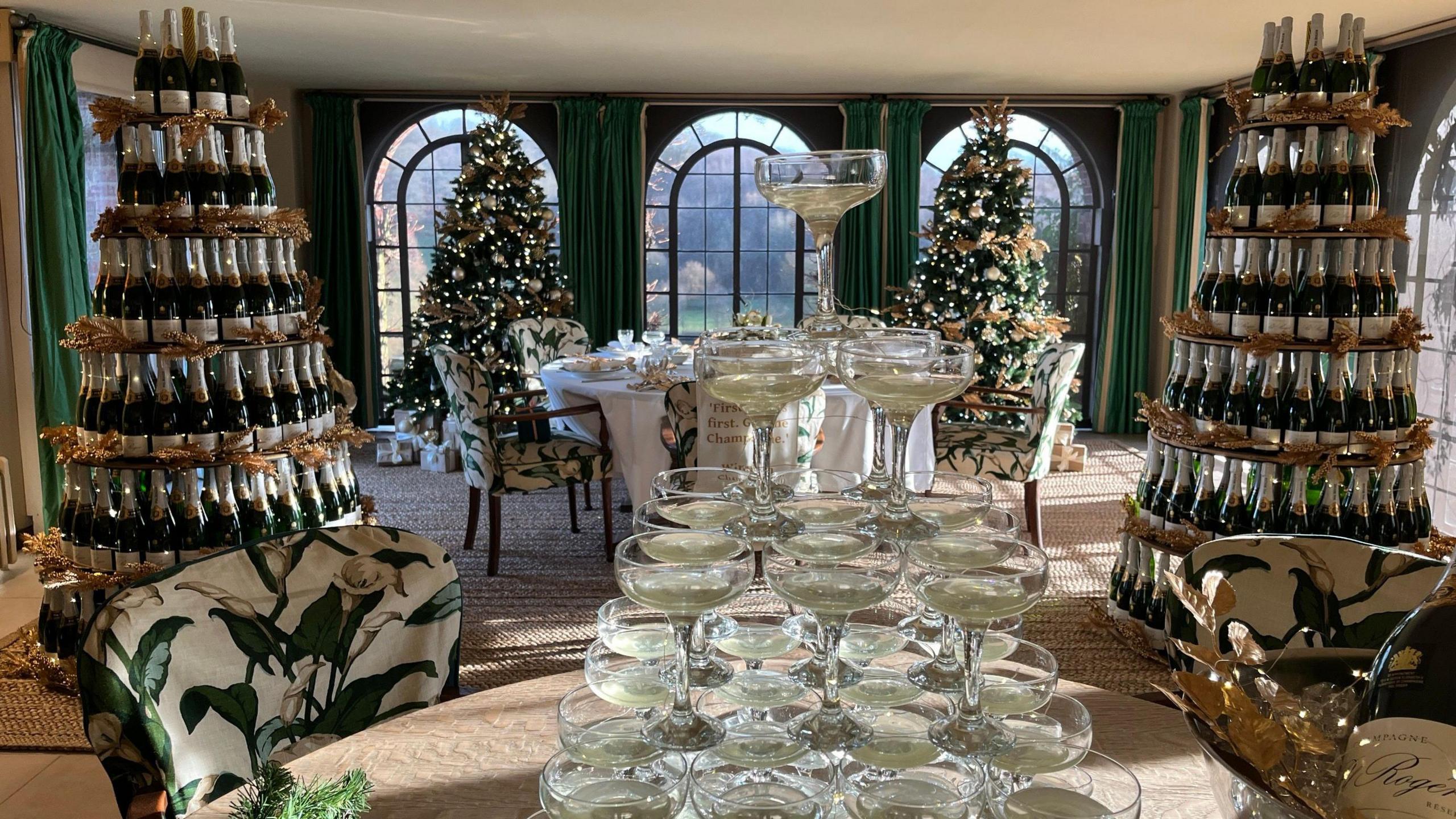 Glasses and champagne bottles stacked in the shape of Christmas Trees