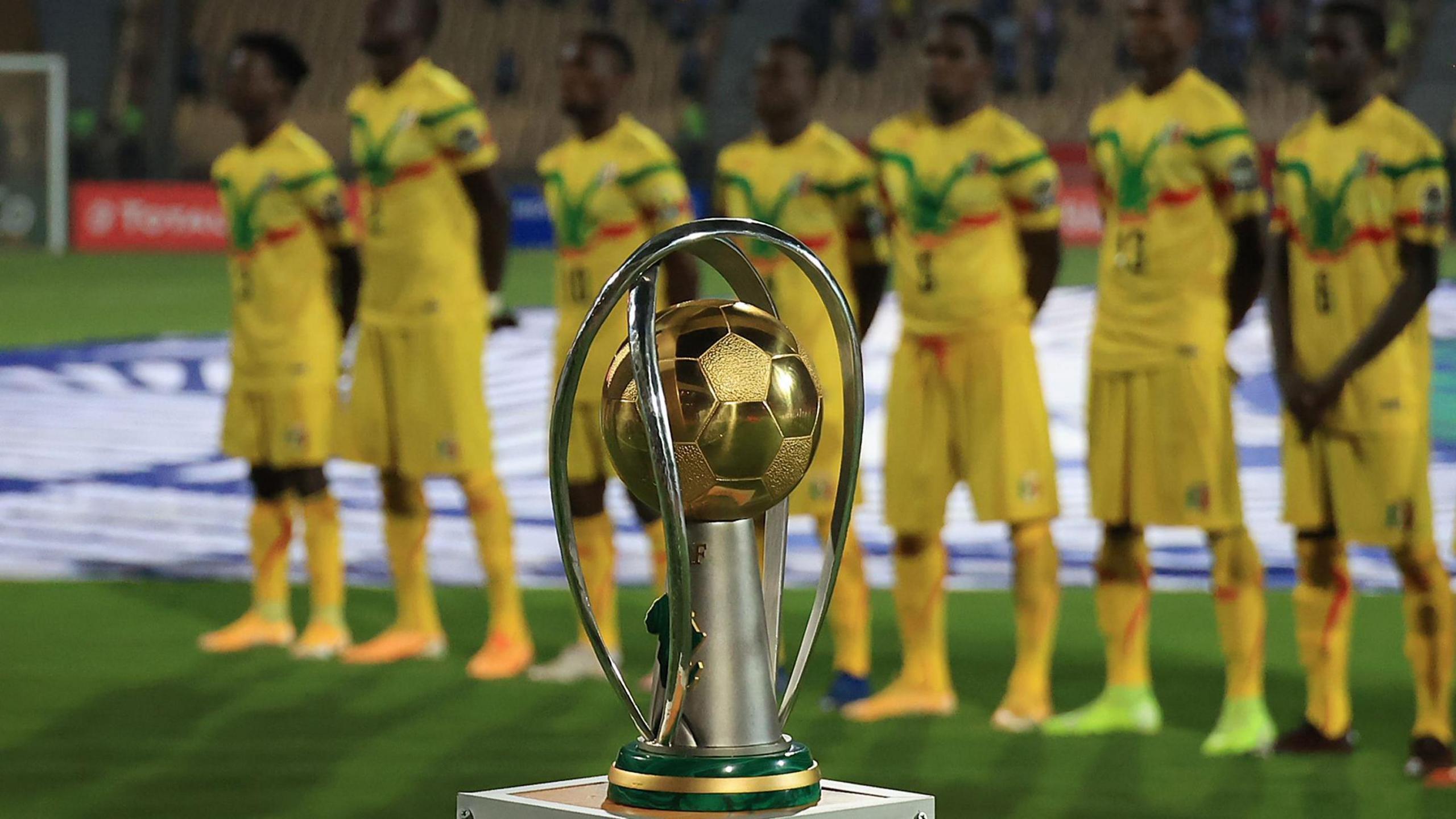 Mali players dressed in yellow, green and red kit stand behind the African Nations Championship (CHAN) trophy ahead of the final against Morocco in Cameroon in 2021. 