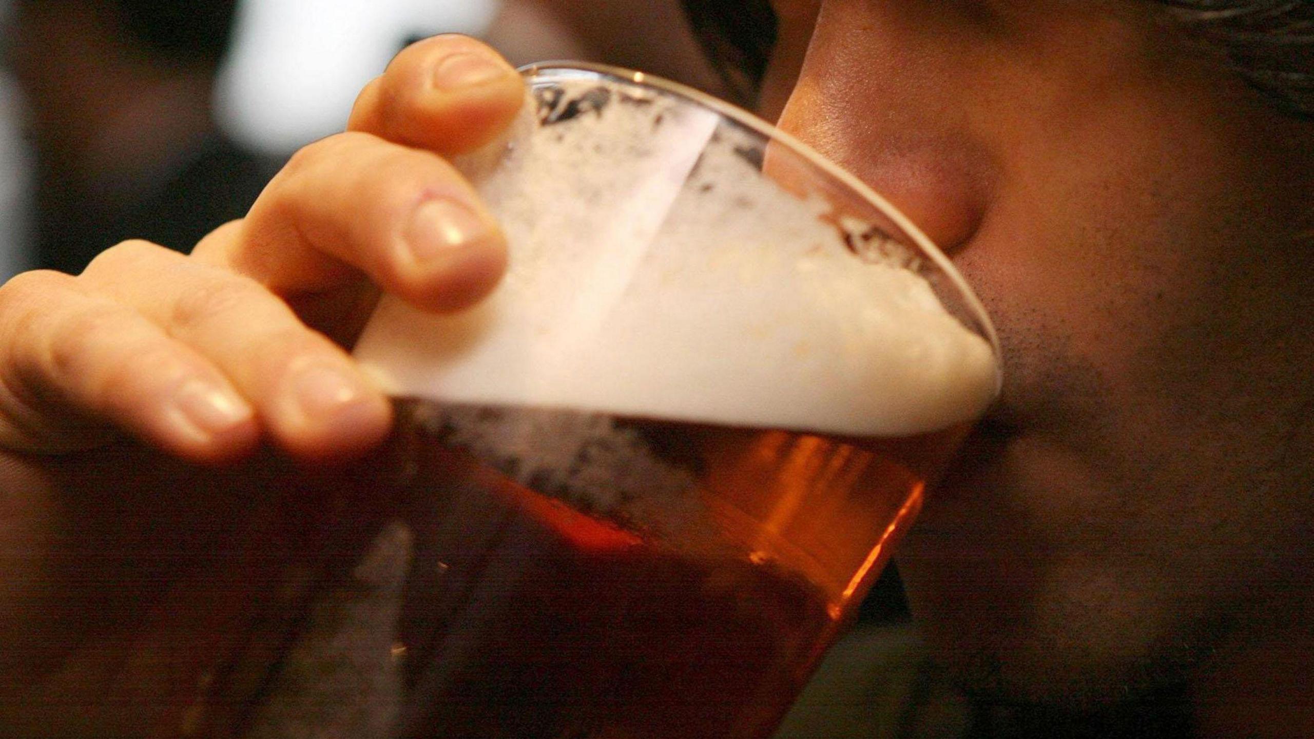 A man raising a pint of beer to his mouth.