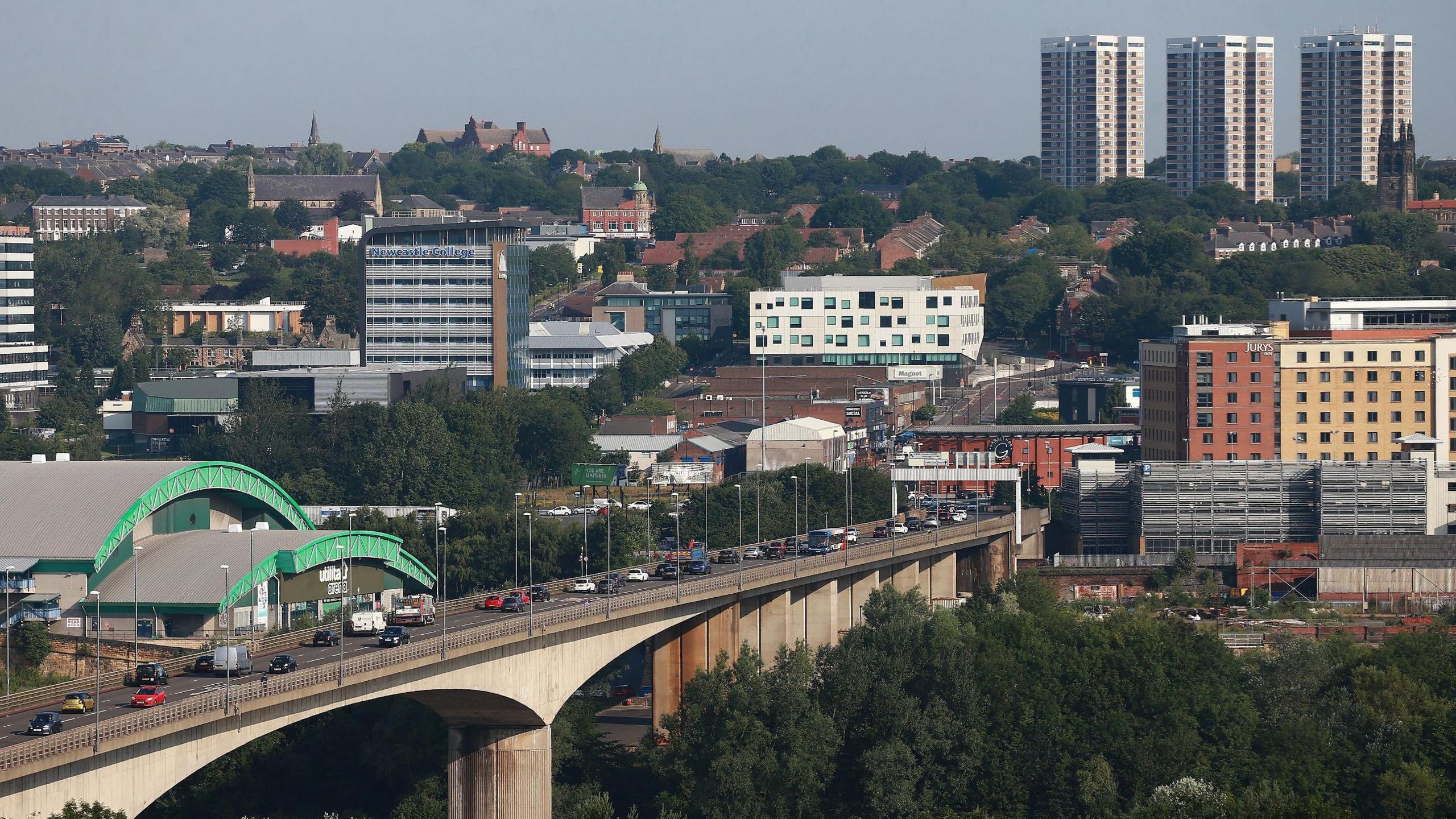 Vehicles travelling across the Redheugh Bridge. It is a concrete structure. Newcastle Arena is on the left-hand side of the image.