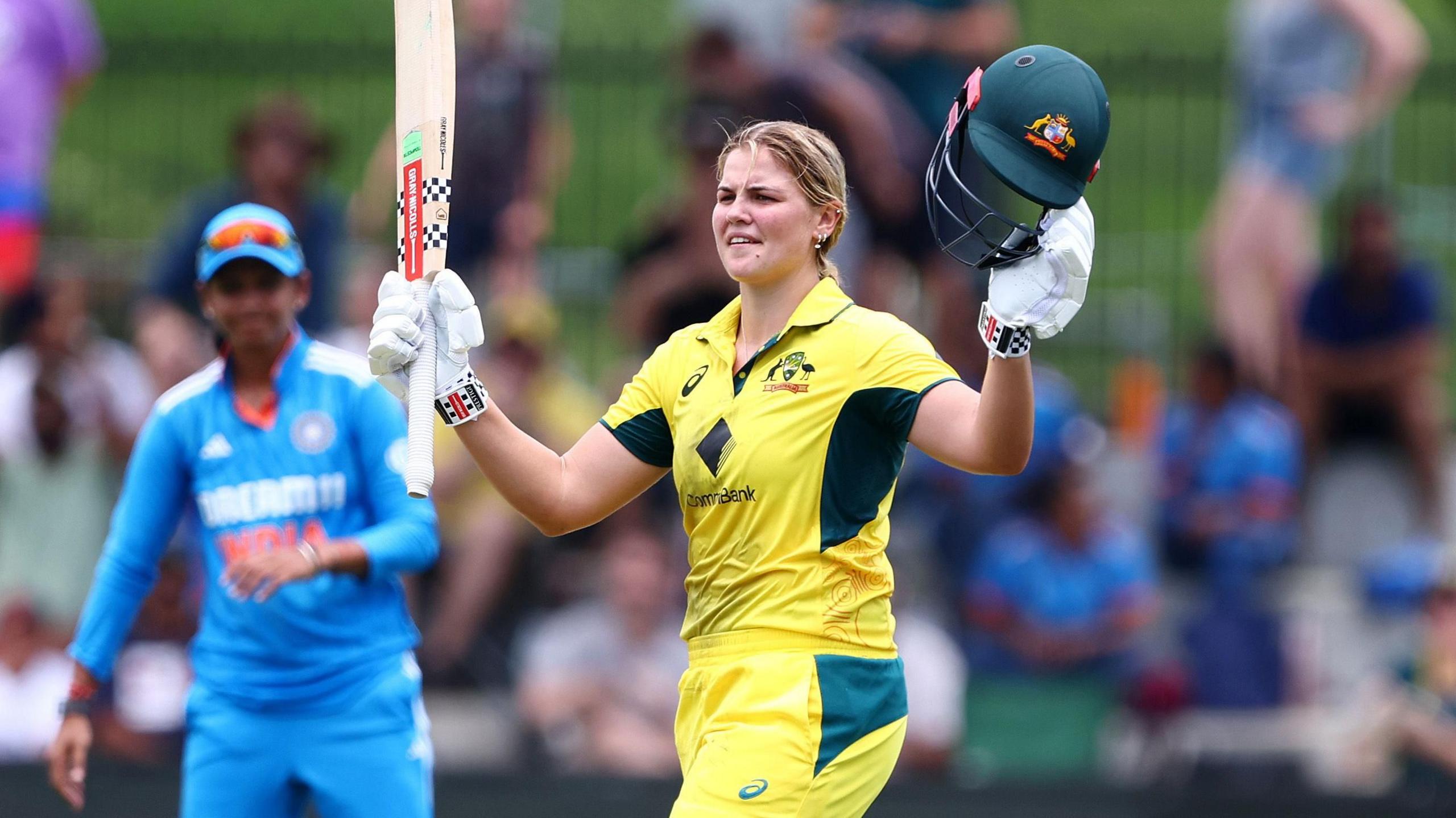 Georgia Voll raises her bat to acknowledge the crowd after making her maiden ODI century