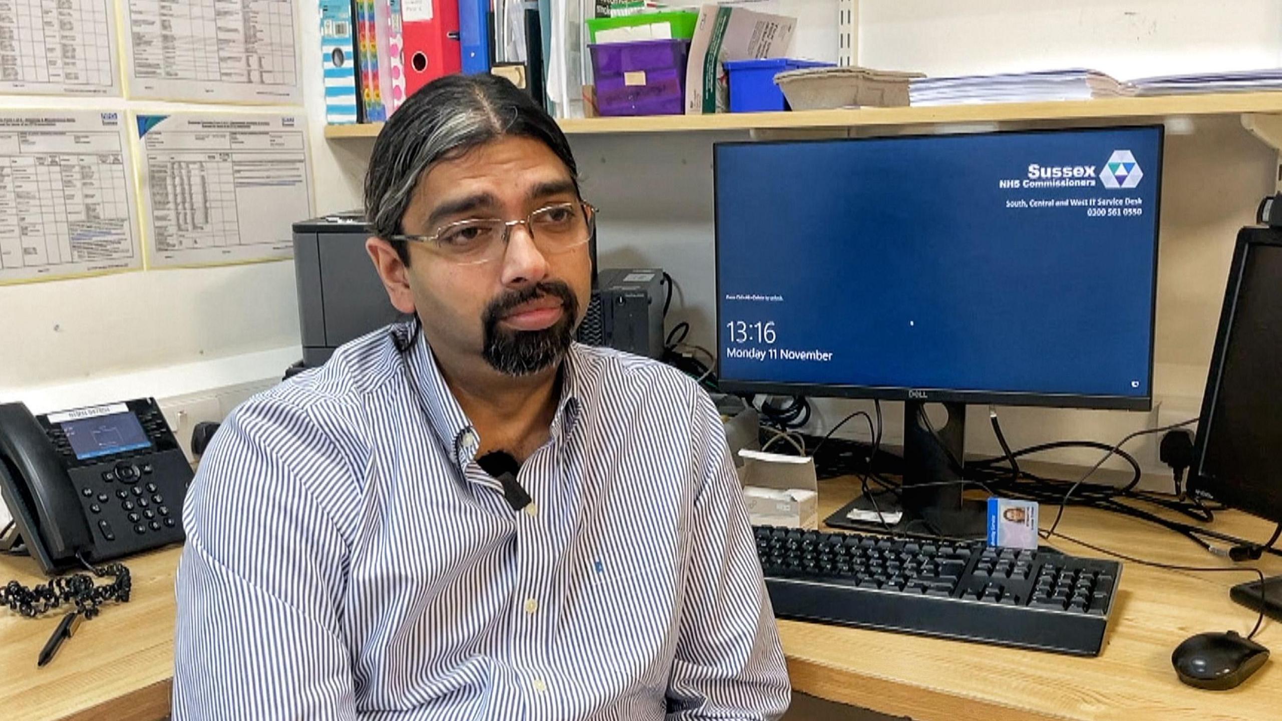 Dr Bikram Raychaudhuri sits at his desk in a GP surgery