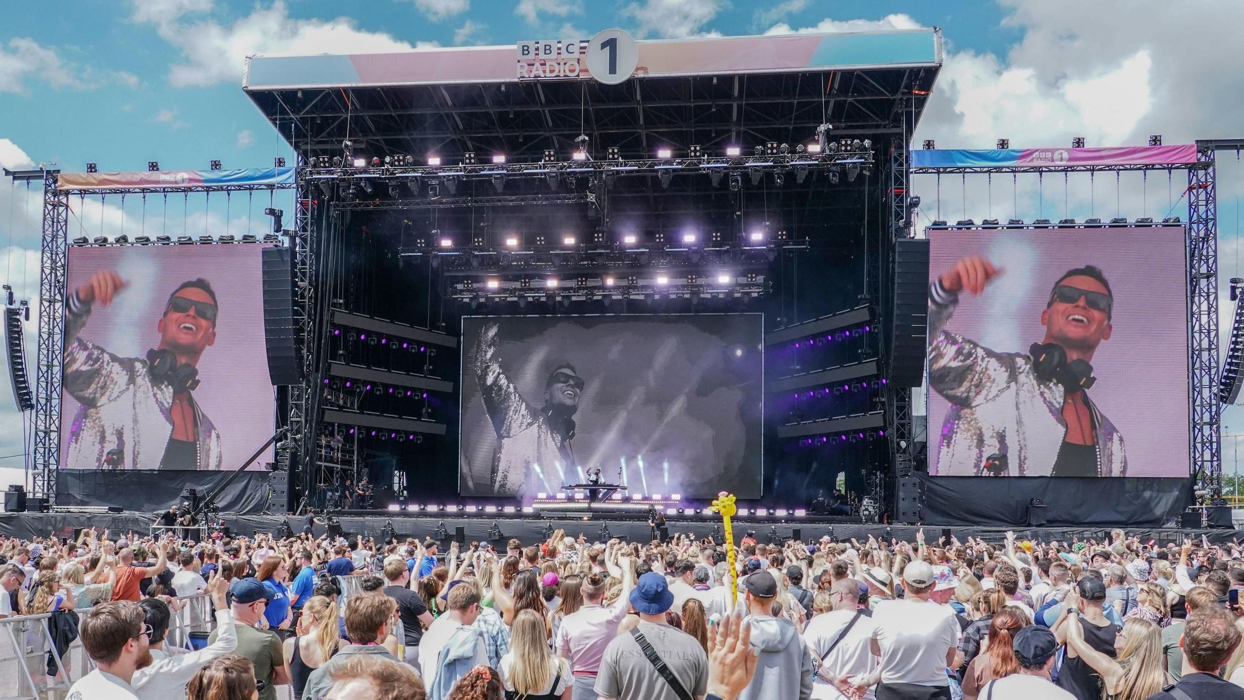 Joel Correy performing at a large stage in Luton with a large crowd before