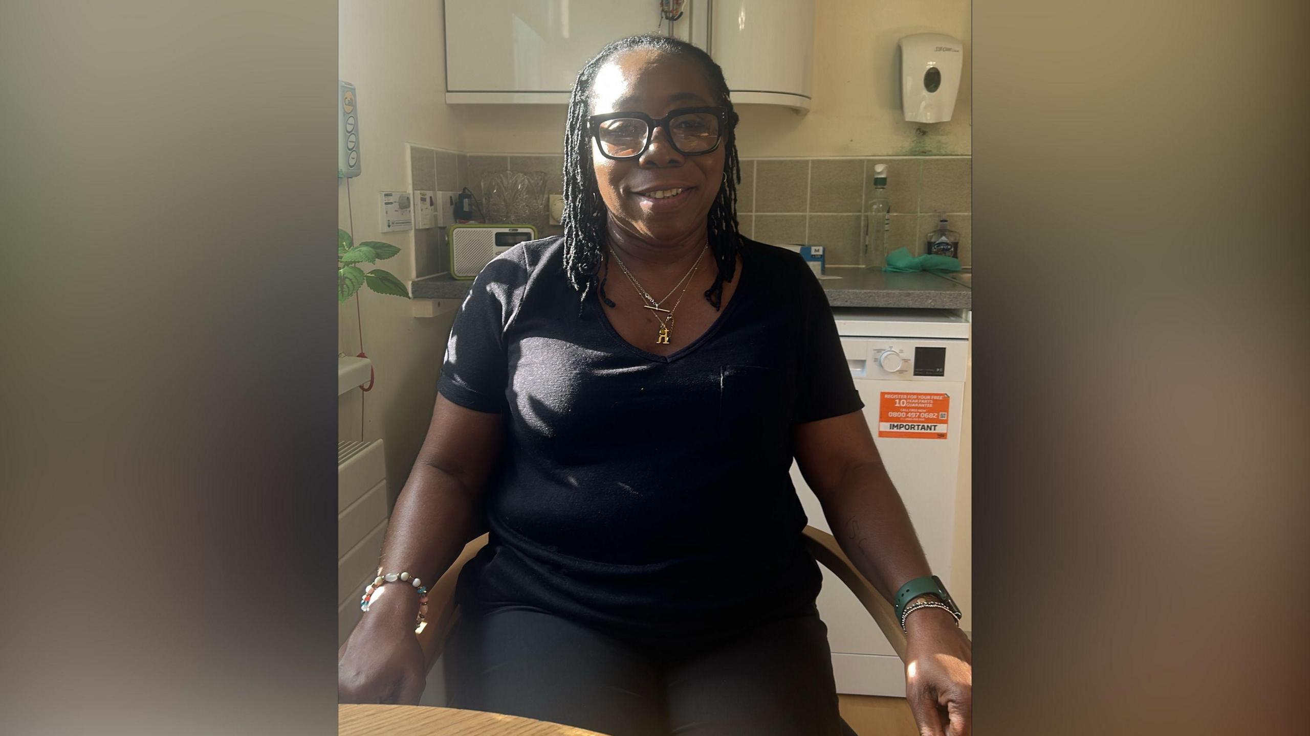 A smiling woman sits in a chair