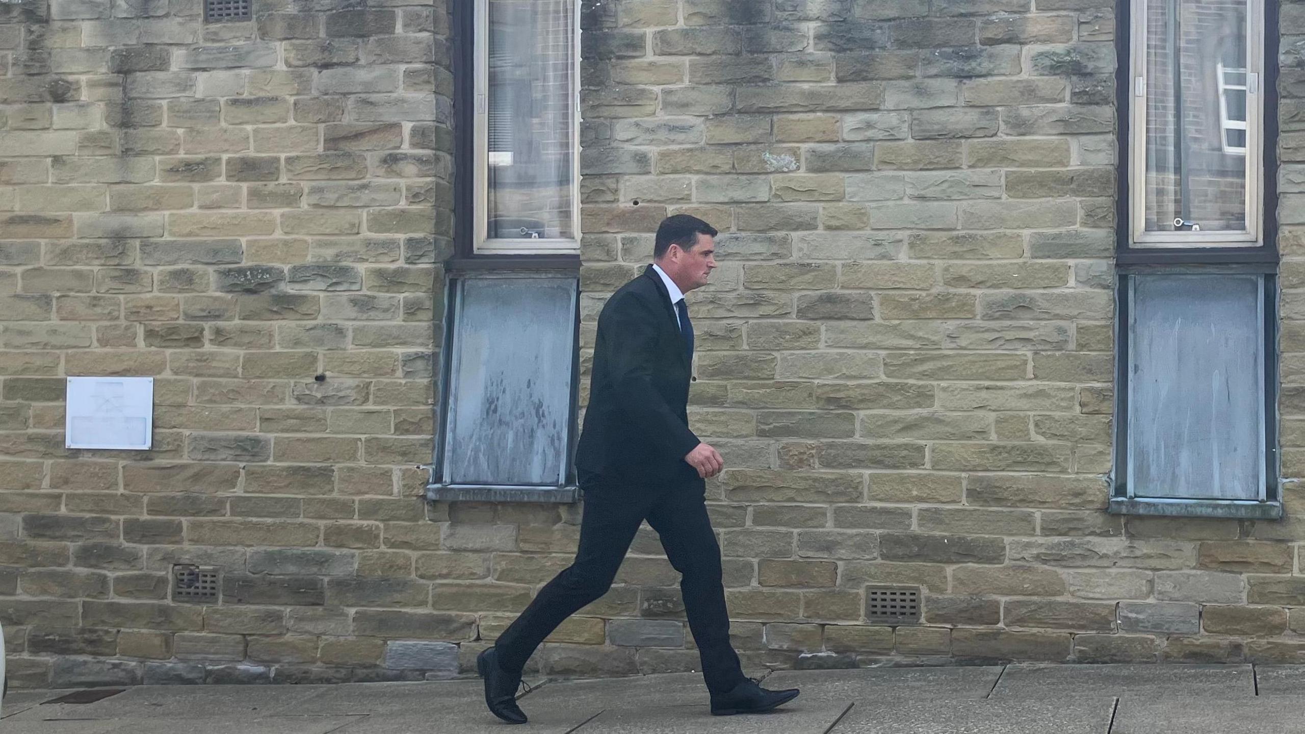 Racster Dingwall, pictured arriving at court in a black suit. He has black hair and is of average build.