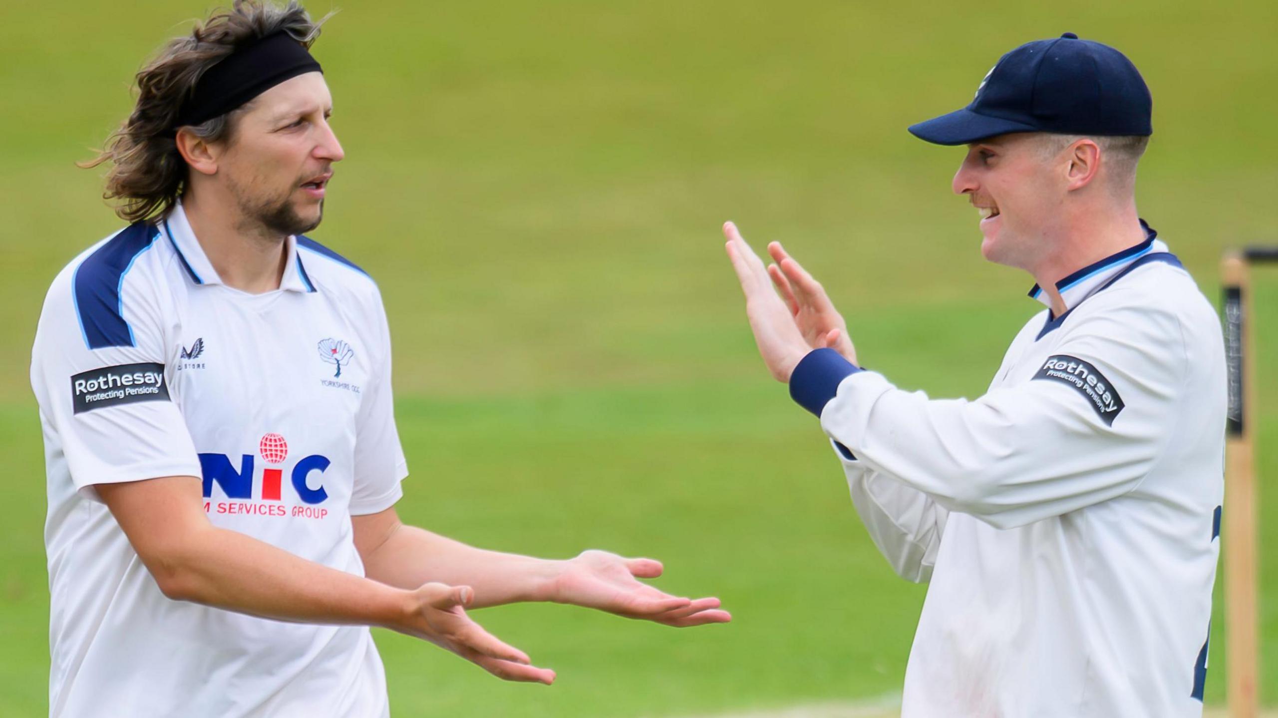 Jack White, wearing cricket whites, gives a low five to another Yorkshire player