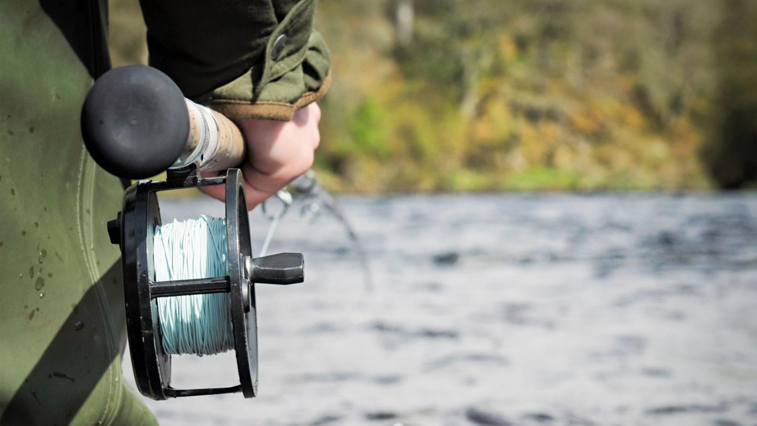 A fishernman with a rod and line by a river