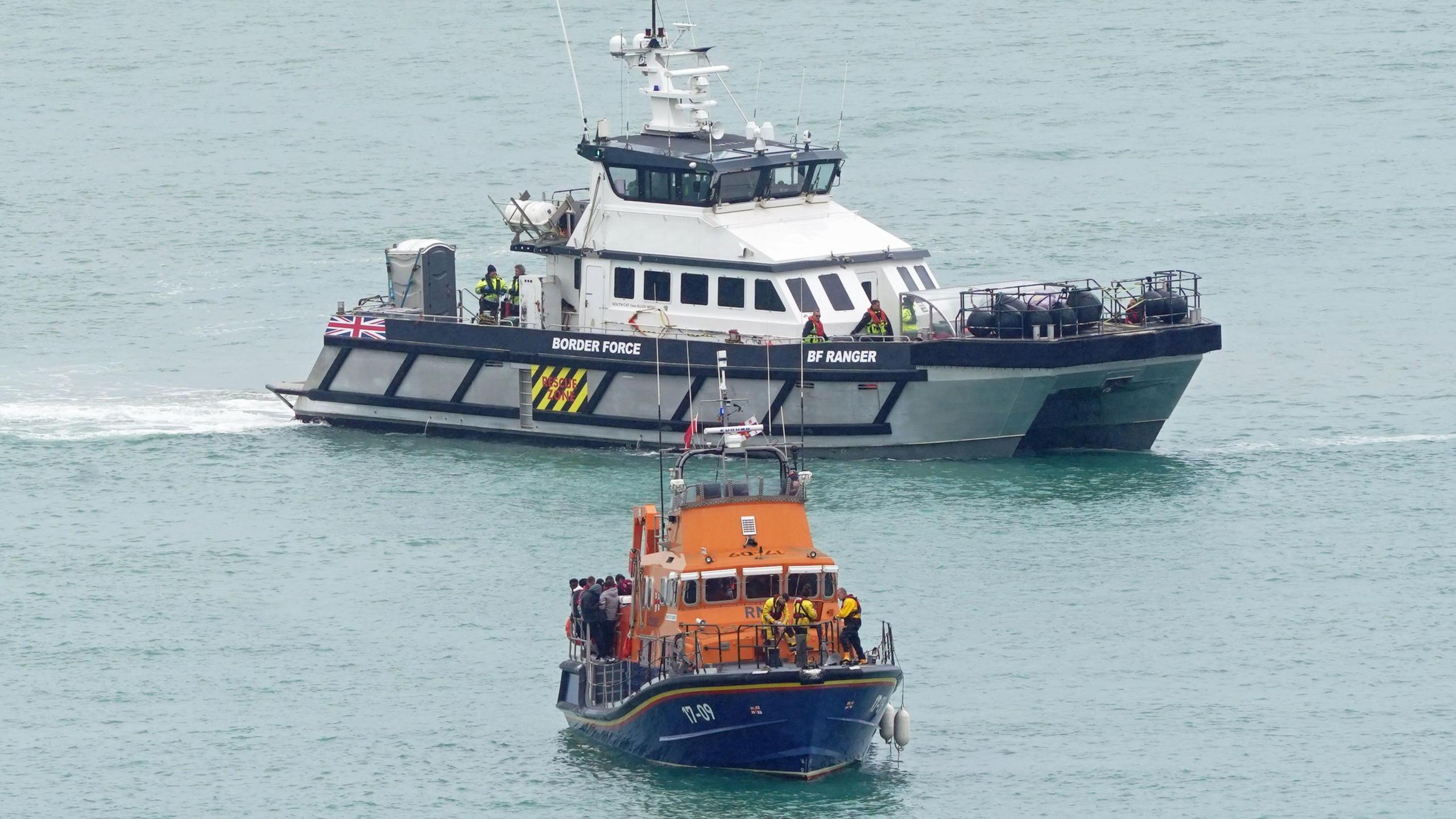 An RNLI boat and a Border Force vessel with what is believed to be migrants on board