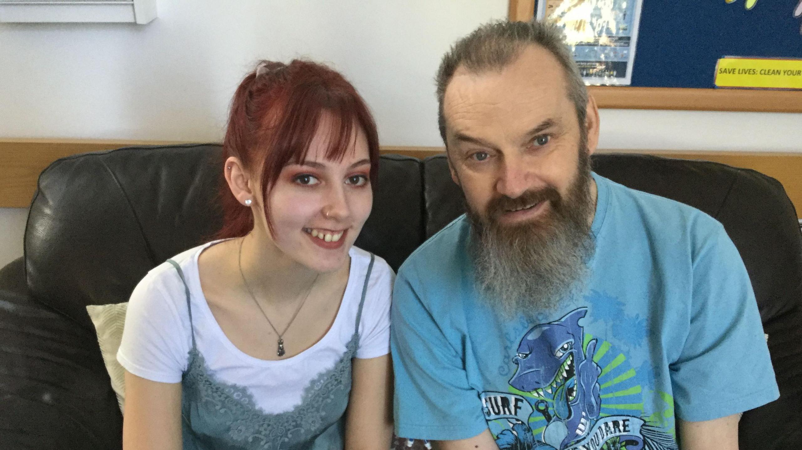 A young woman with red hair and her father - a man with a grey beard wearing a blue T shirt