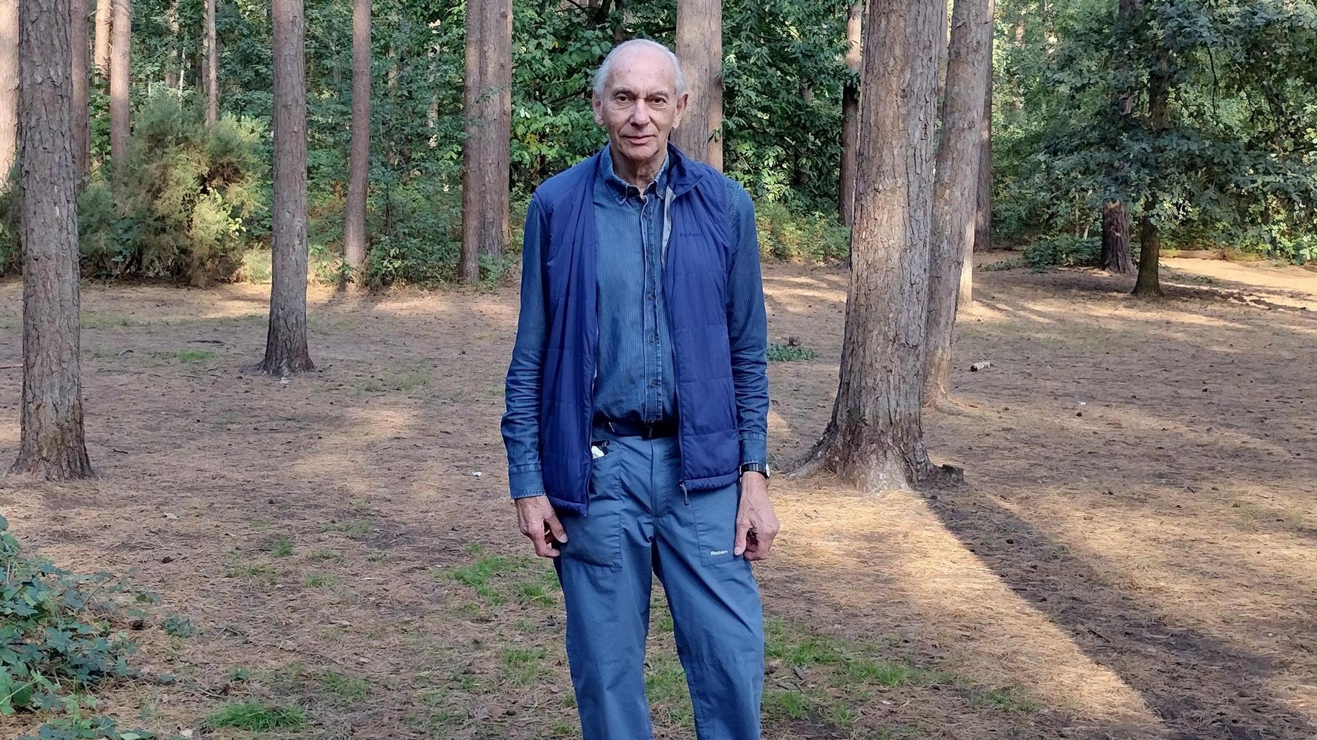 Professor Peter Beck, author of 'The War of the Worlds: From HG Wells to Orson Welles and Beyond', stood in Horsell Common. Peter is wearing all blue and has white hair.
