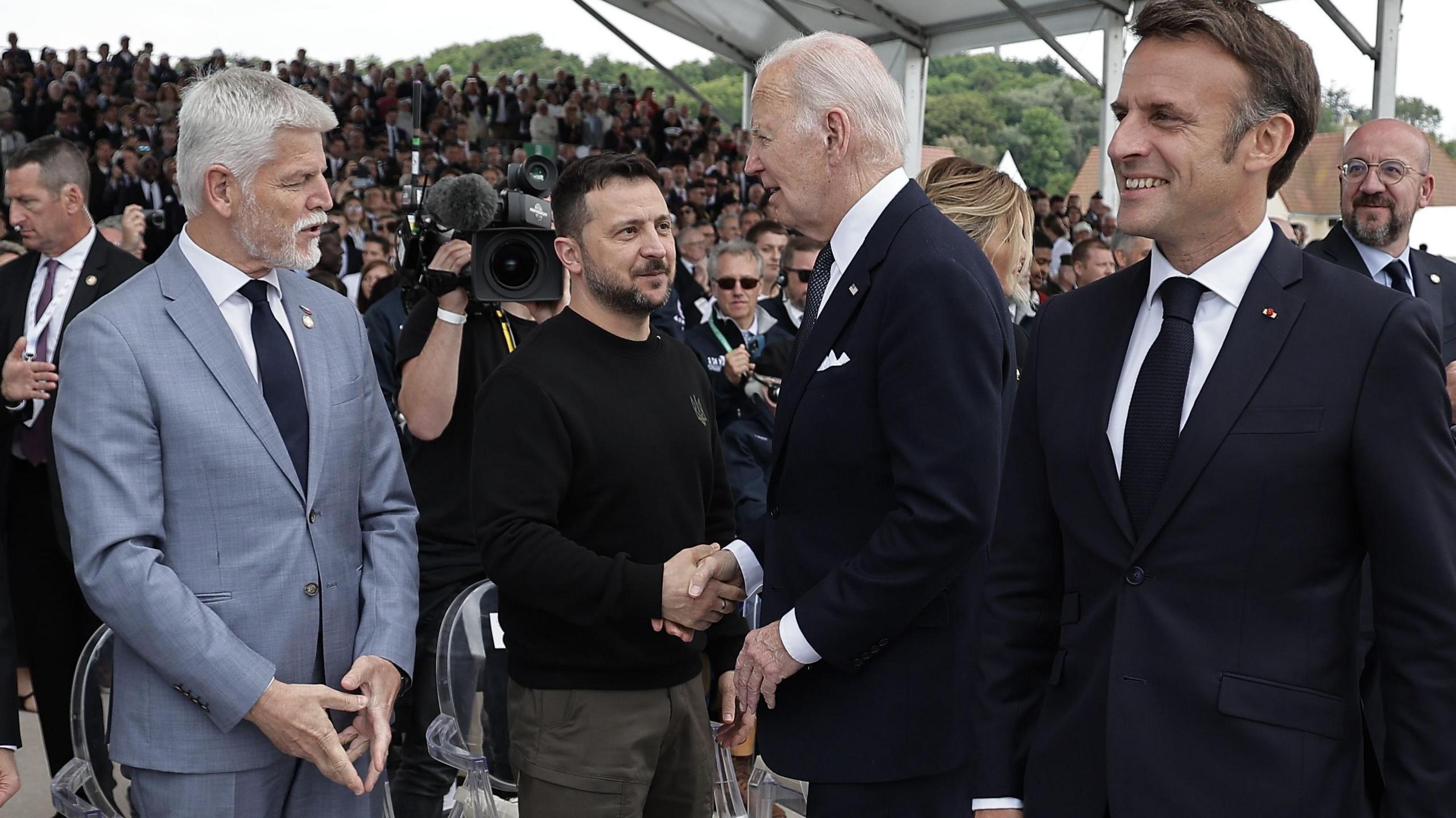 Ukrainian President Volodymyr Zelensky and US President Joe Biden shake hands at a D-Day commemoration in Normandy