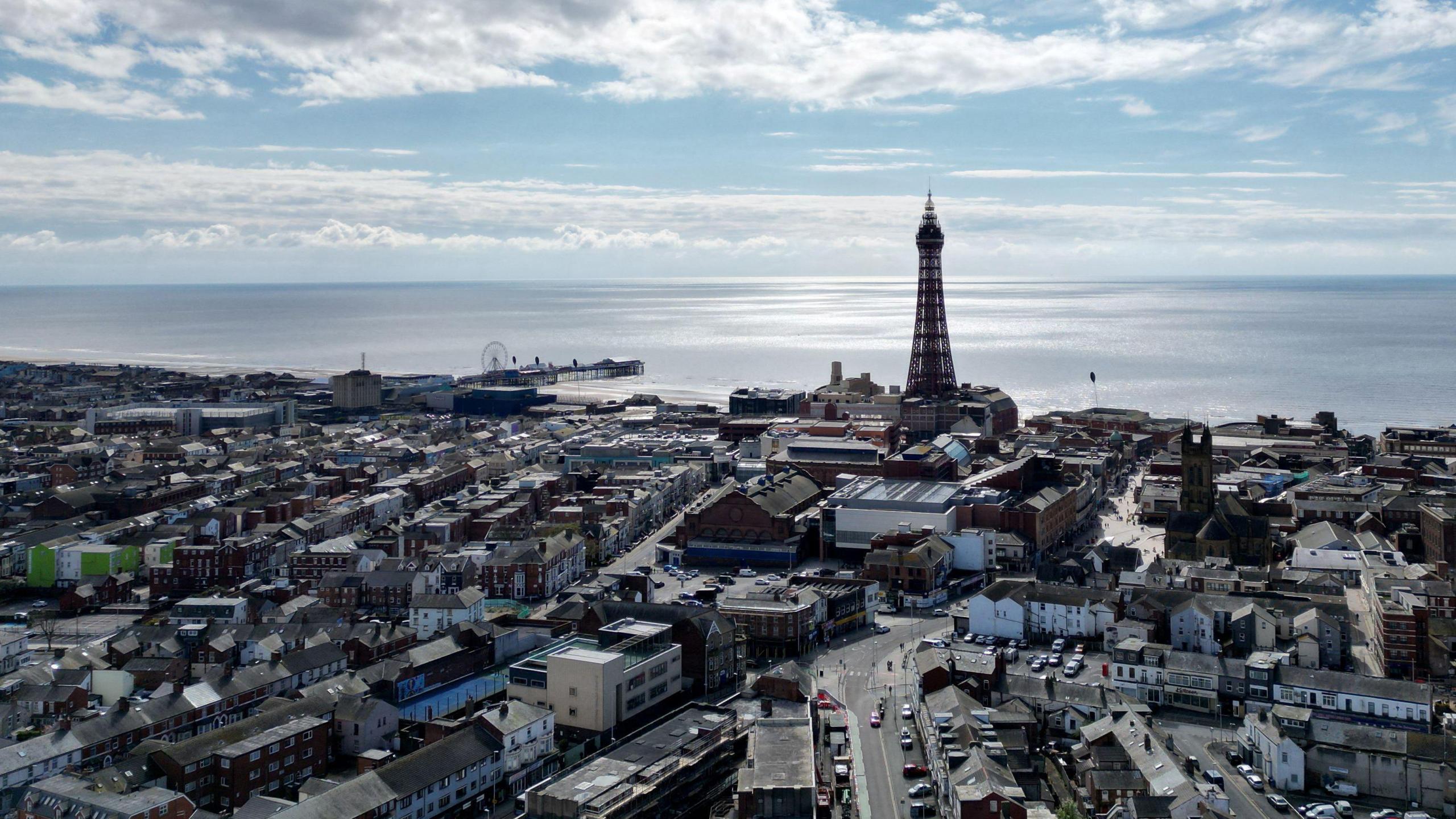 drone view of houses around Blackpool Tower with pier and sea in the backdrop