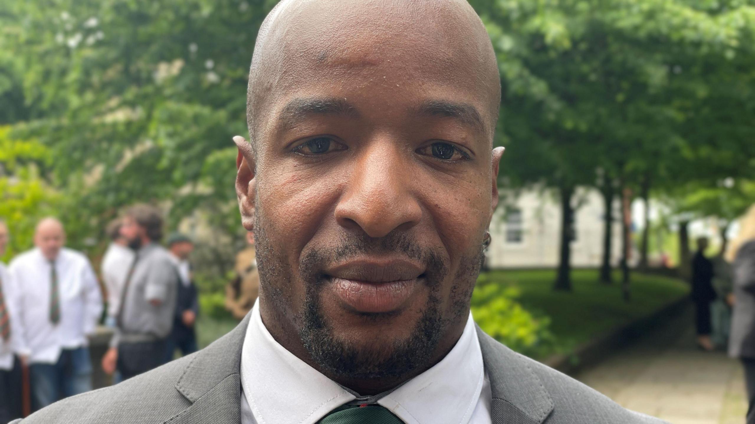 Veiner Gaston in a grey suit standing outside the funeral