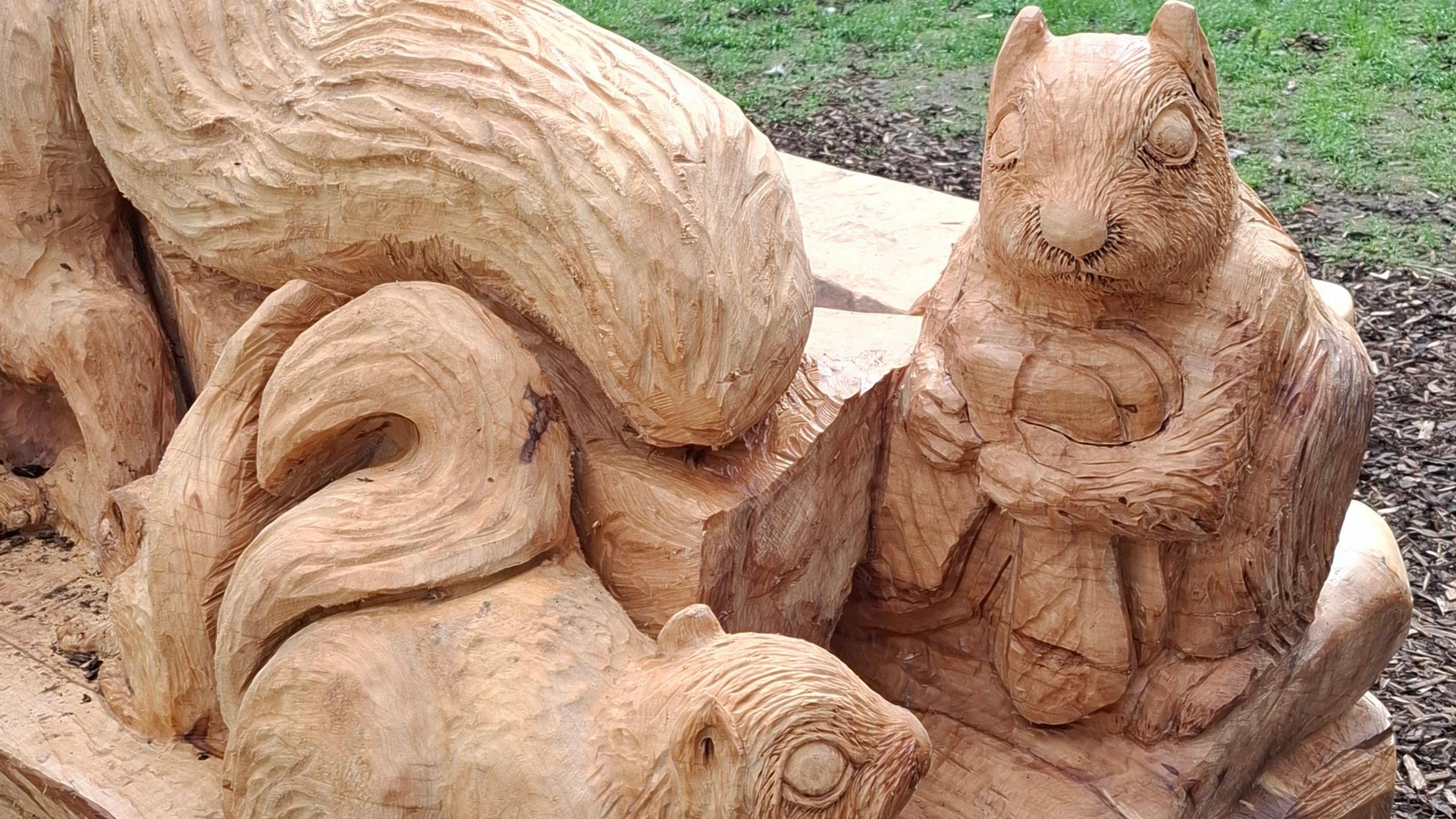 Part of the tree trunk sculpture seen up close. Two squirrels are holding nuts.