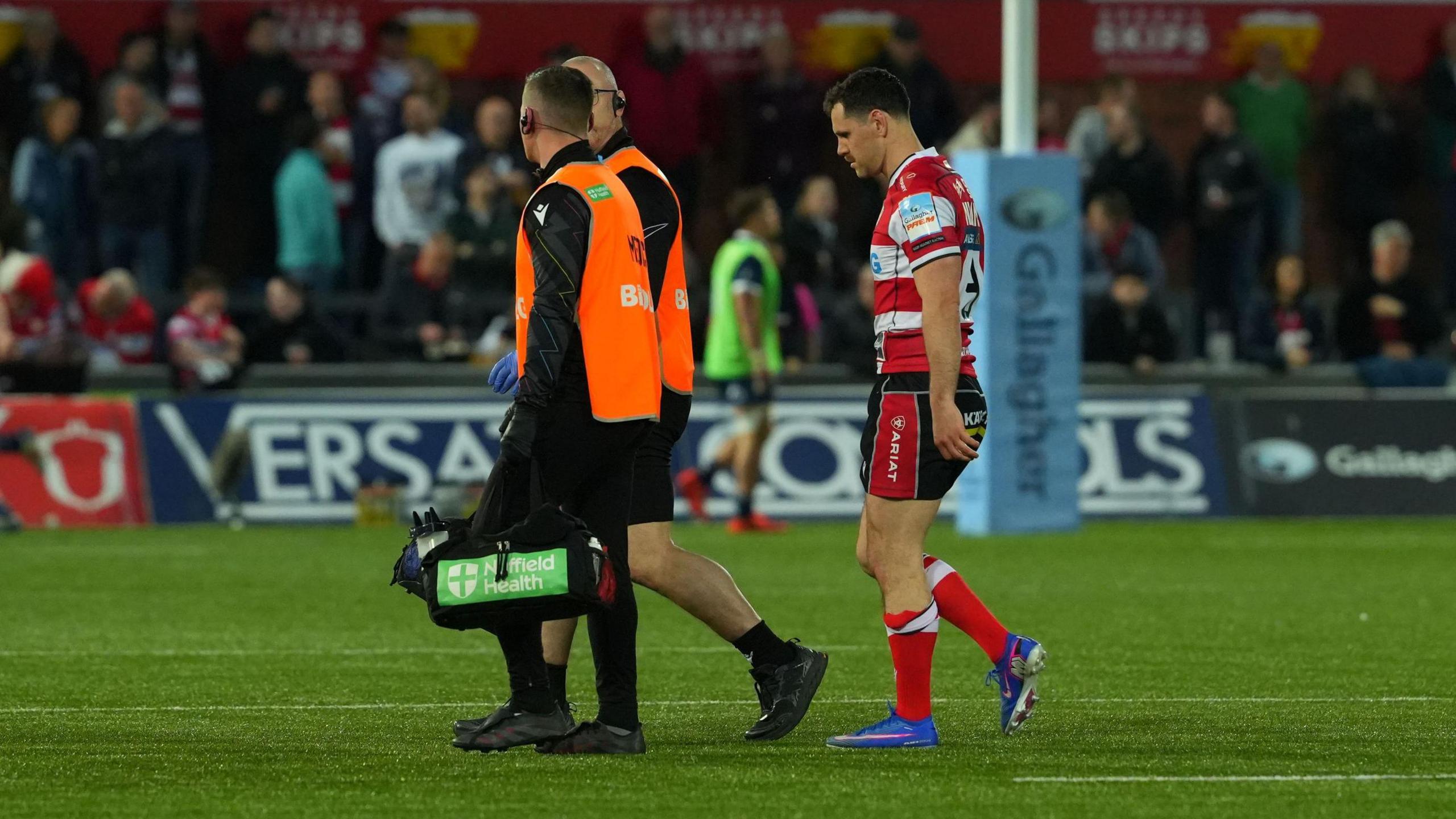 Tomos Williams (right) walks off the pitch of Gloucester v Sale behind two medical staff