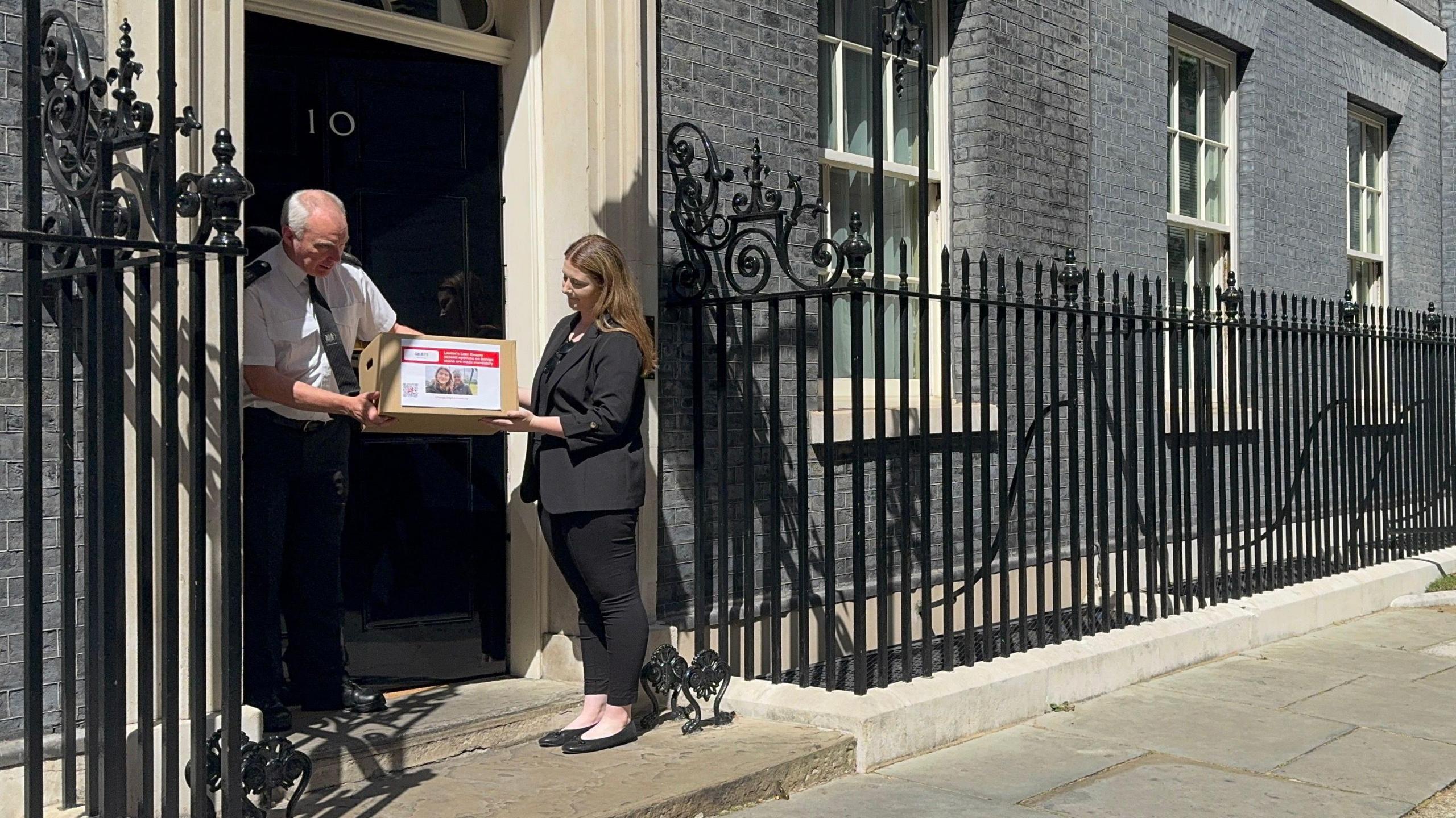 Chloe Hickman passing a cardboard box with a picture of her and her mum on it to a Downing Street official outside Number 10.