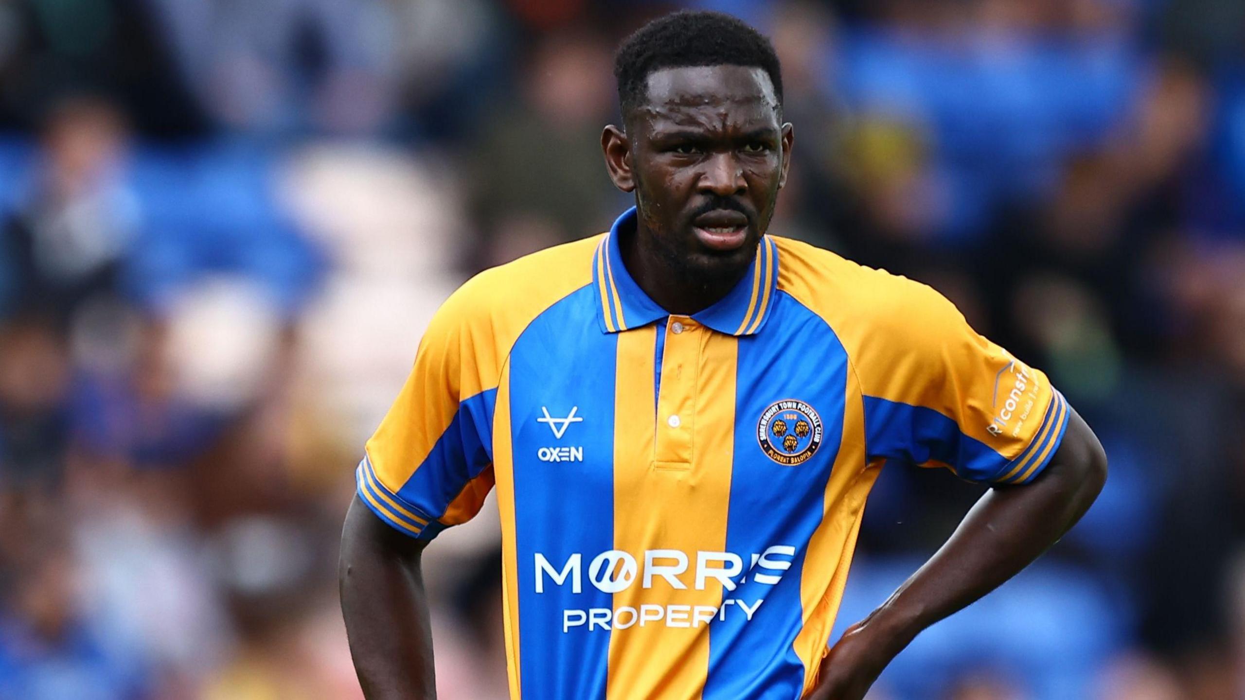 Toto Nsiala stands with his left hand on his hip watching play during a match