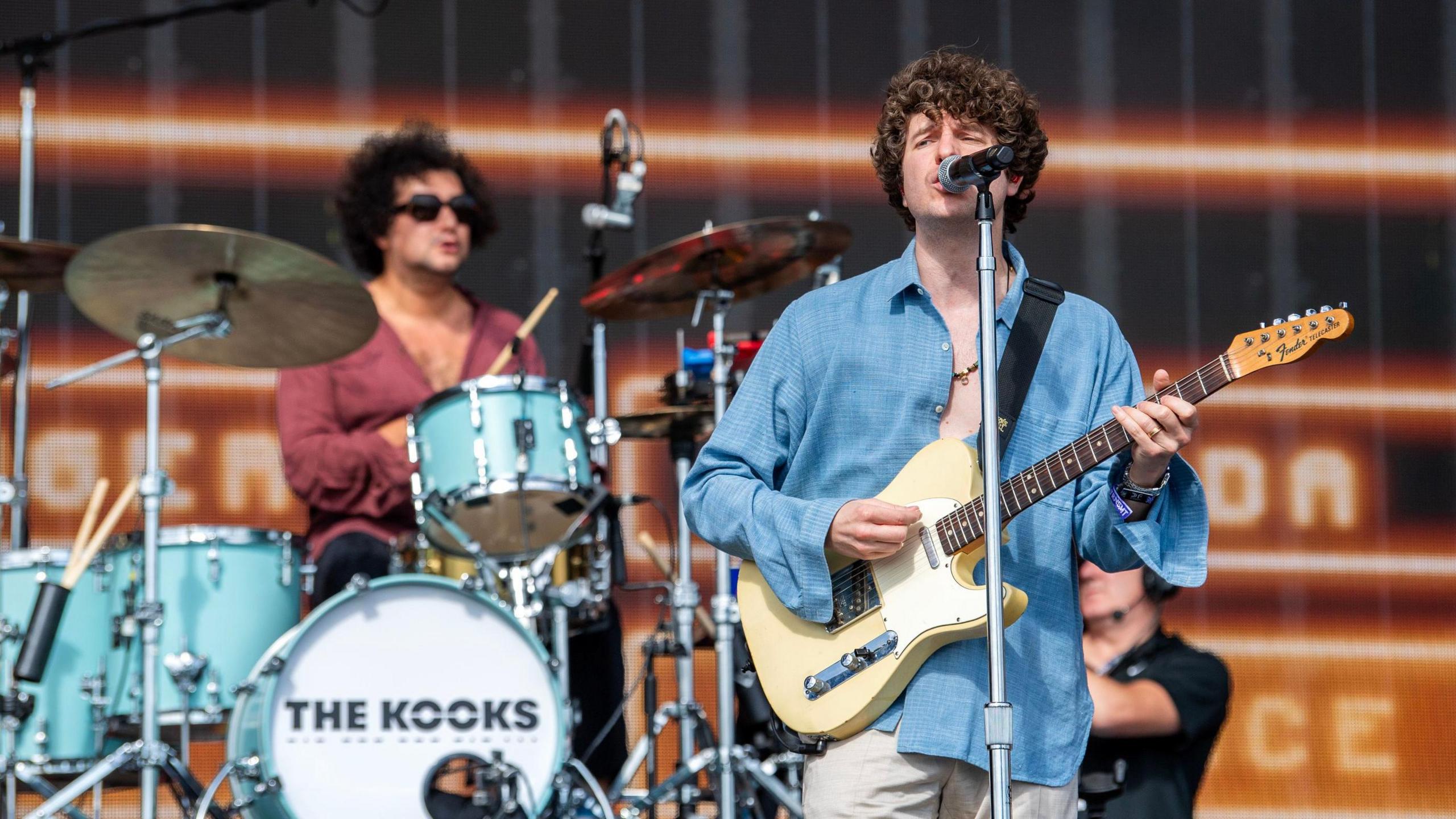 The Kooks performing on a main stage at an event.