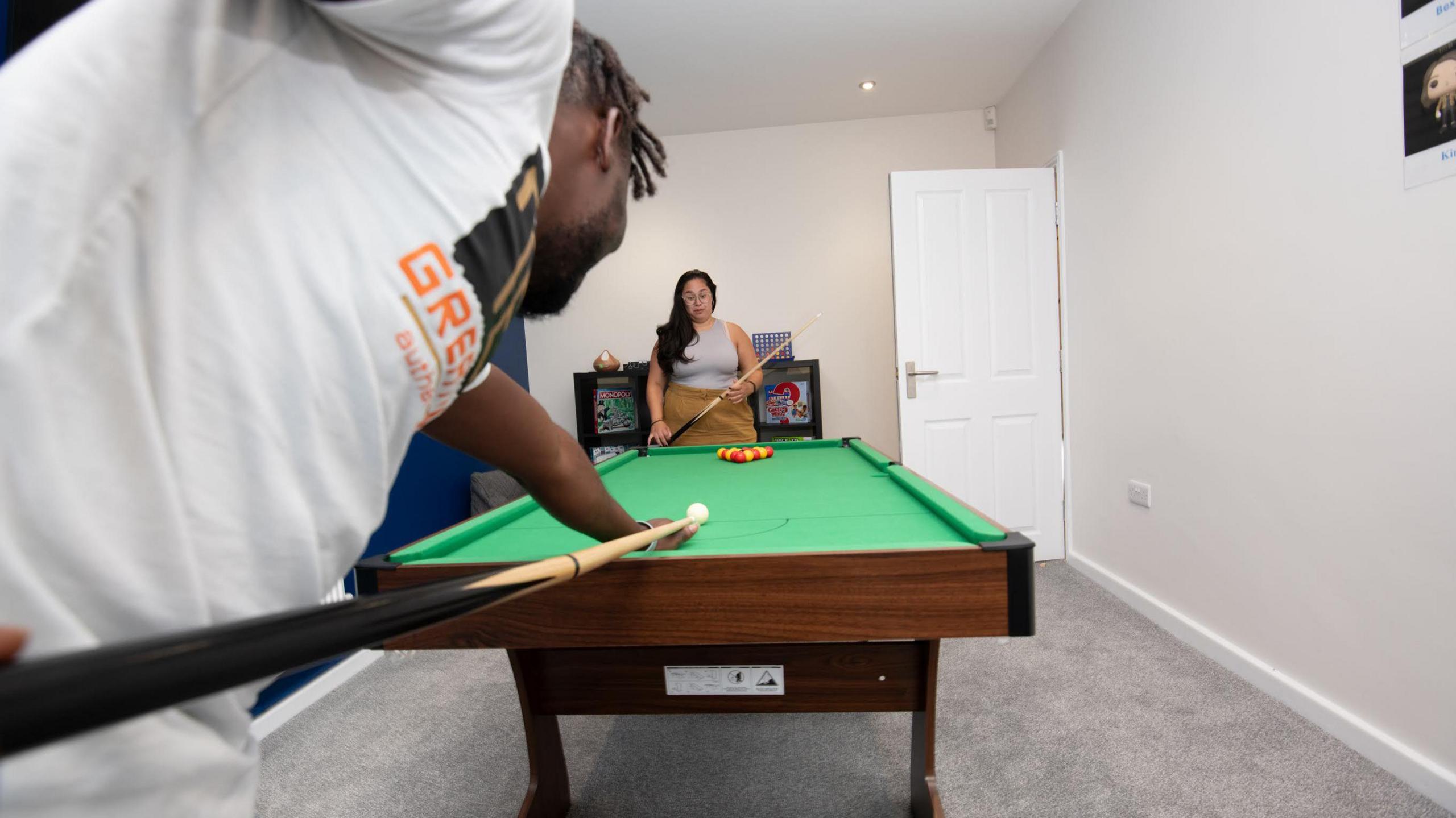 A man and a woman playing pool