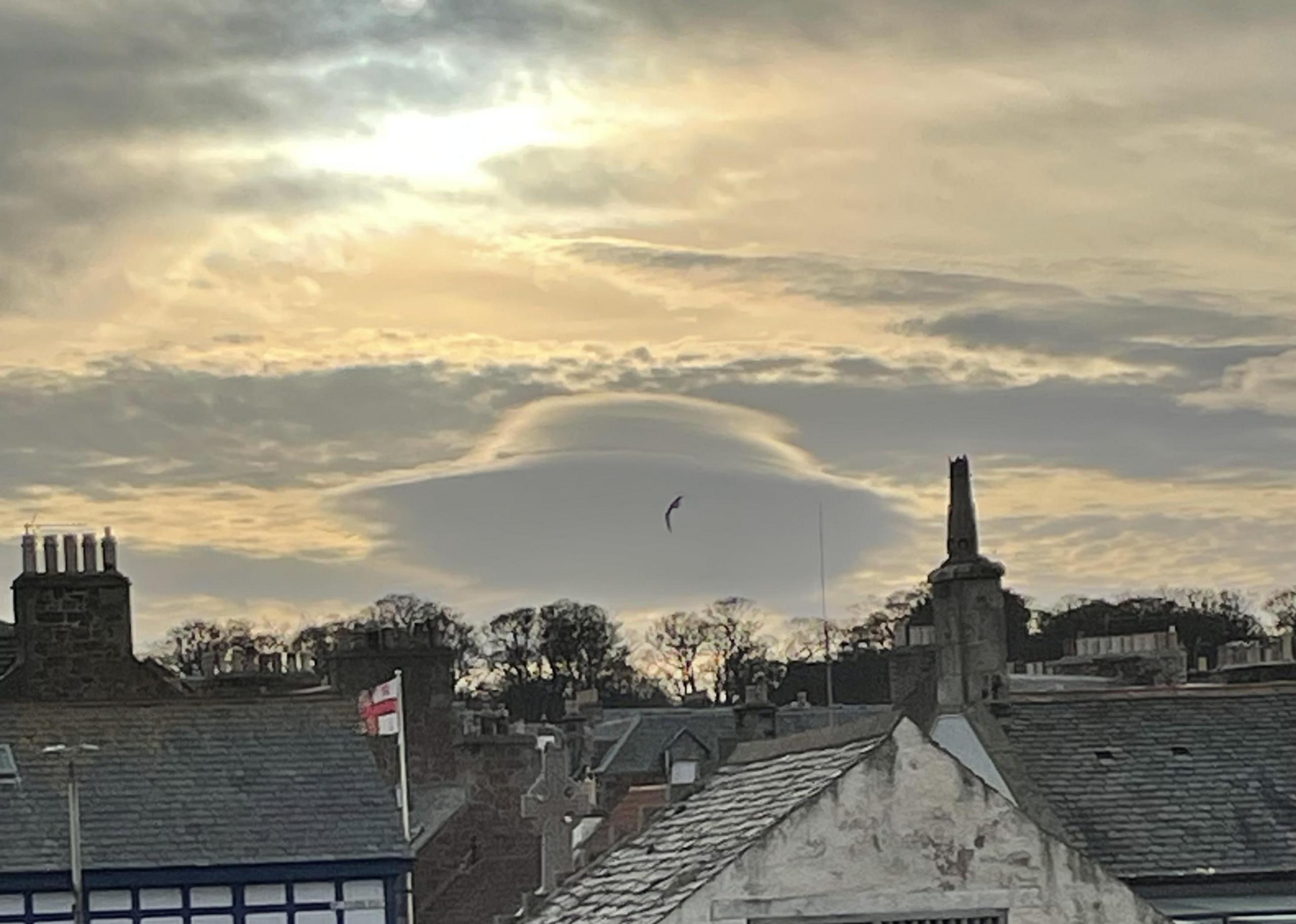 A lenticular cloud behind buildings in the foreground