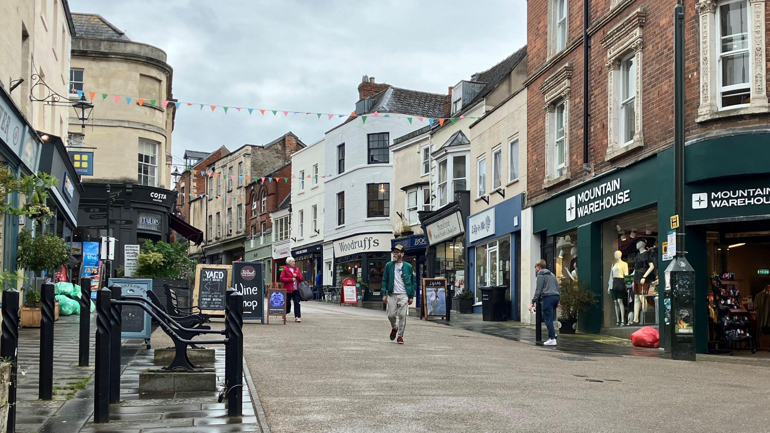 Stroud High Street on a quiet day, with shops and a man walking down the road