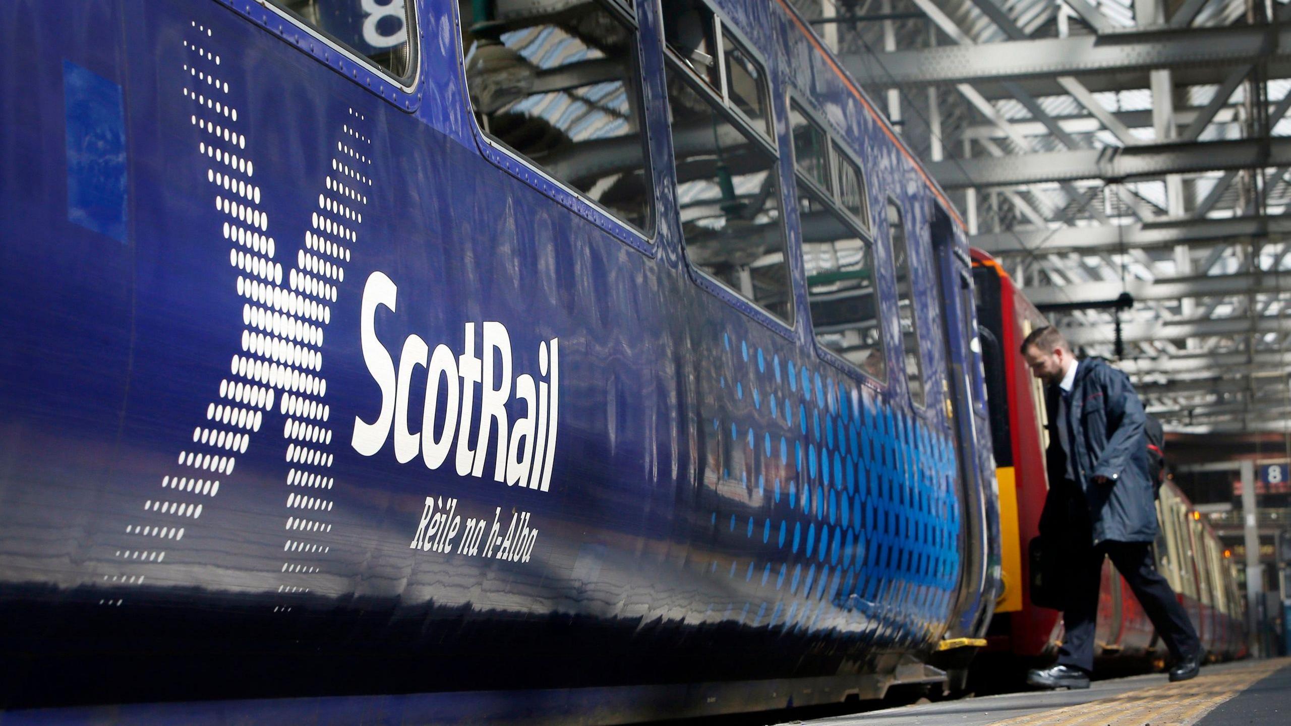 Image of a ScotRail train with one passenger getting on board