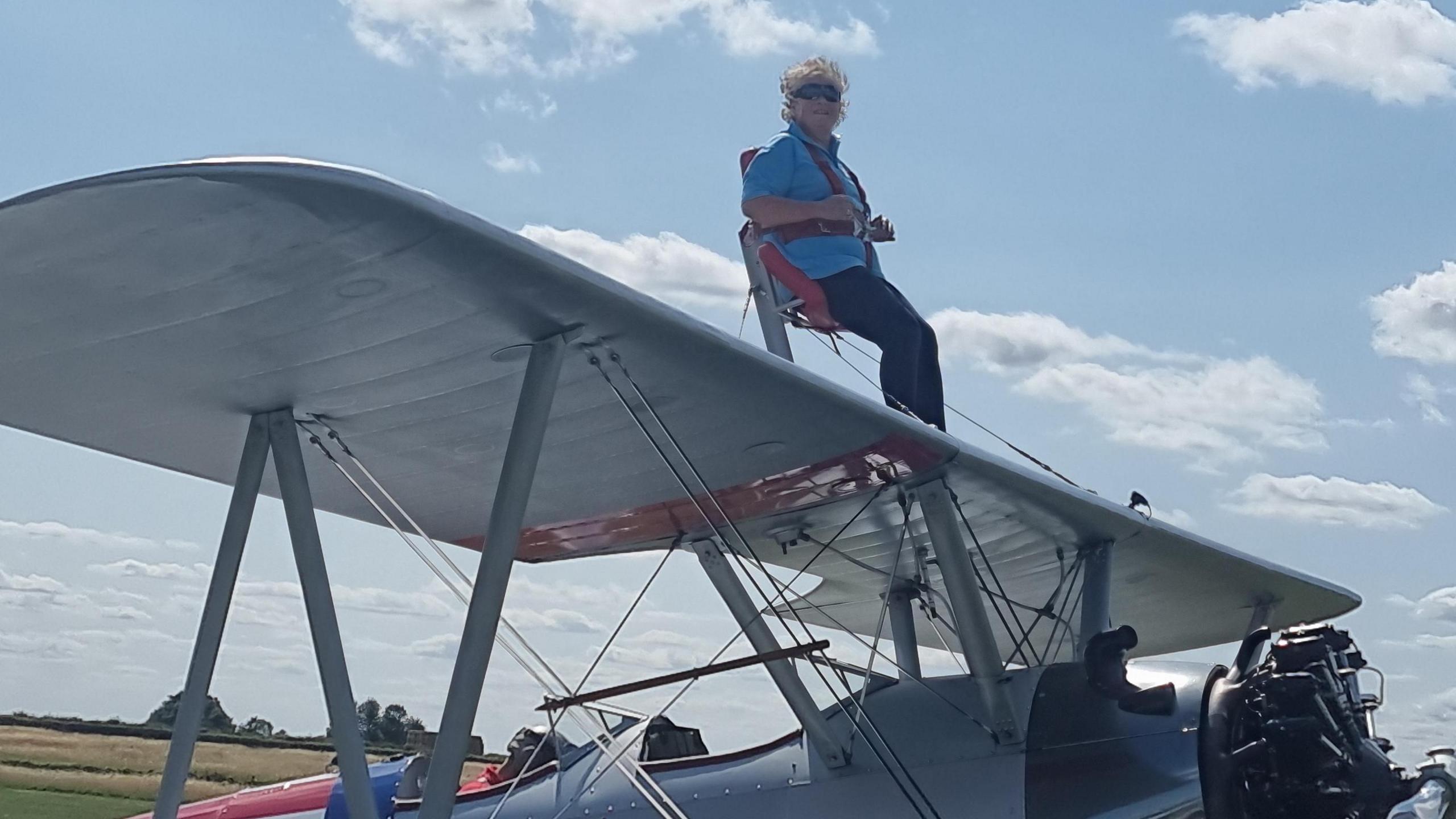 Mel Griffiths strapped into position on the top wing of a silver biplane