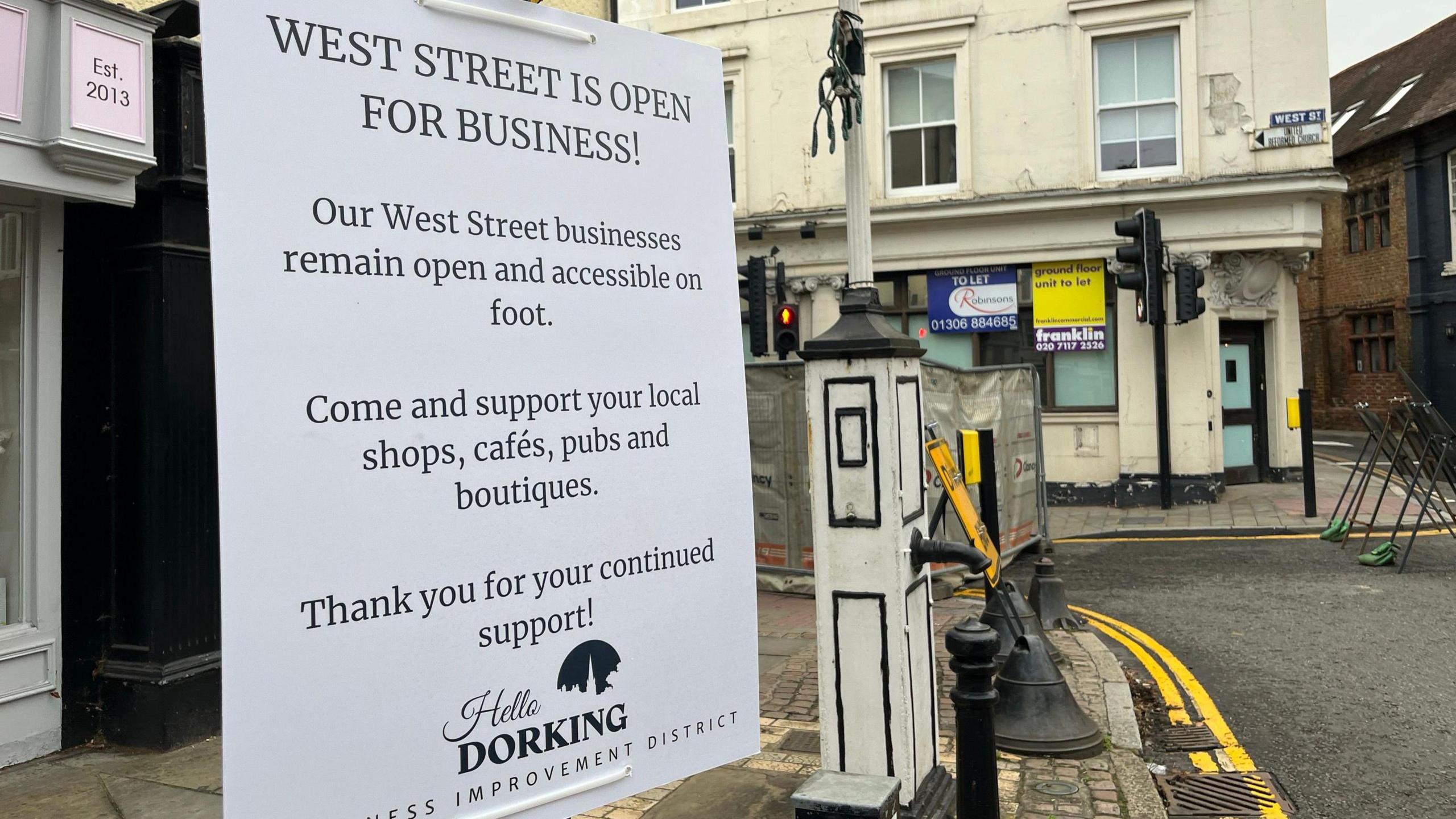 A shop window in West Street, Dorking, with A4 pages printed off to spell out the word open.