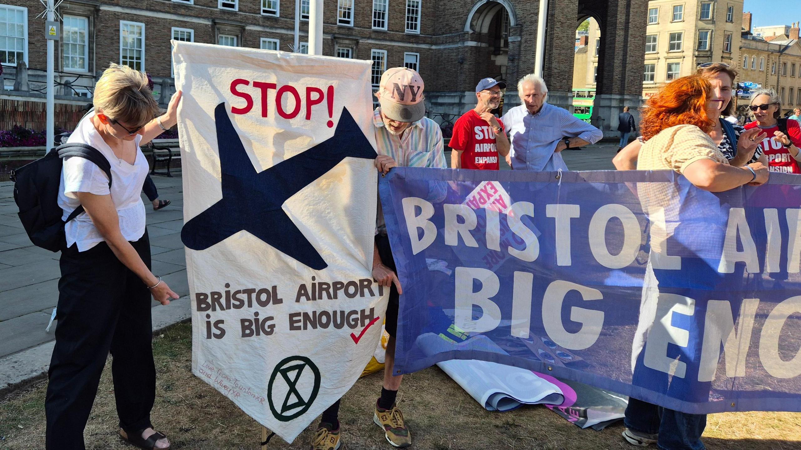Protestors standing outside City Hall on the grass, holding up banners and signs which read "Bristol Airport is big enough". 