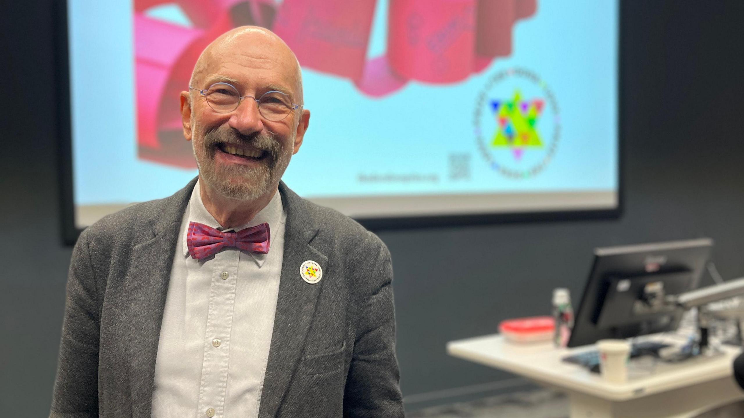 Prof Rainer Schulze stands in front of a screen with a star logo for the Dora Love Prize