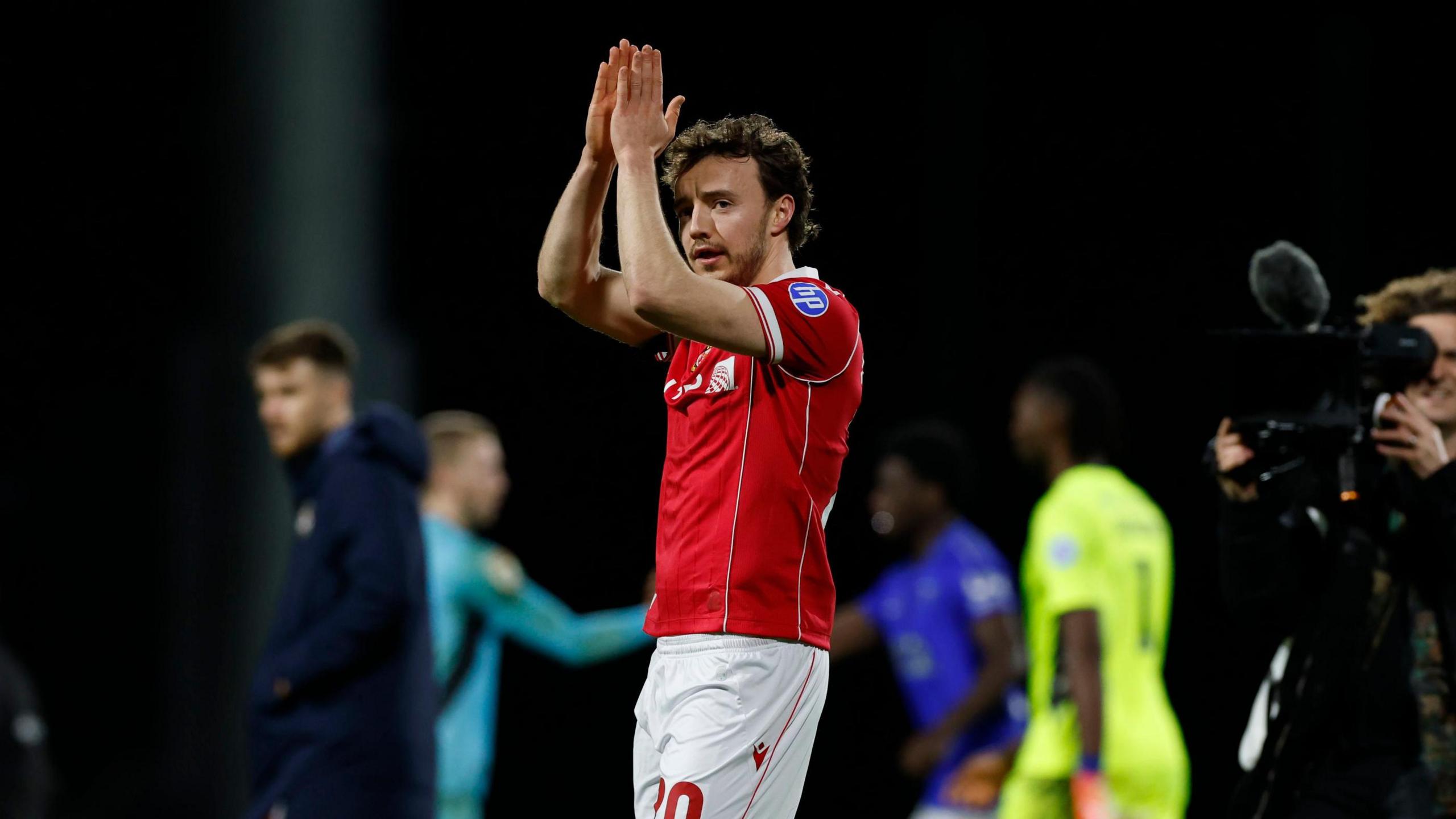 Wrexham midfielder Ollie Rathbone applauds fans