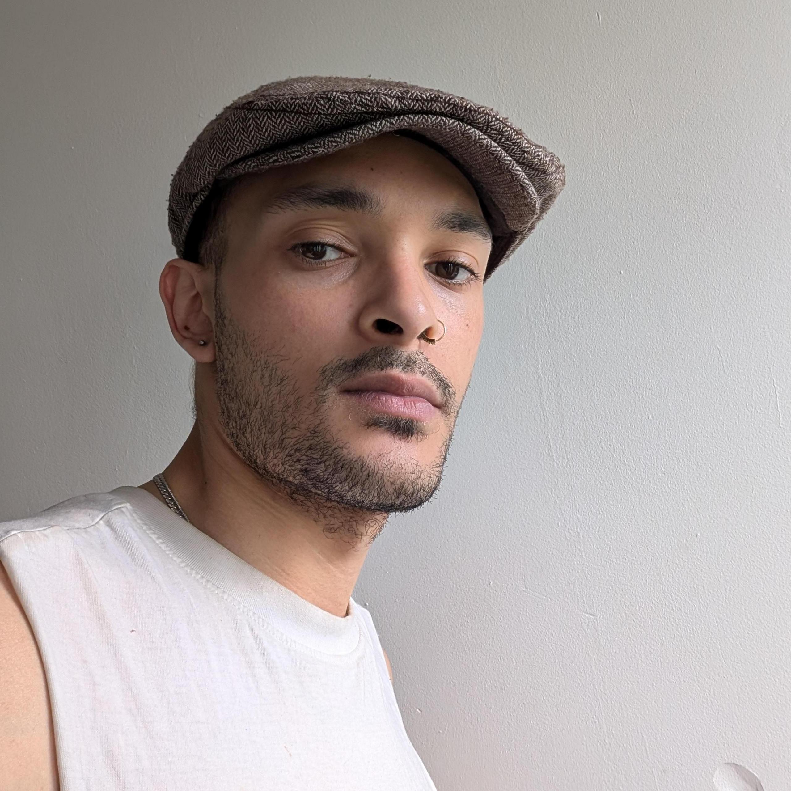 Musician Duke Keats pictured wearing a flat cap and white T-shirt. 