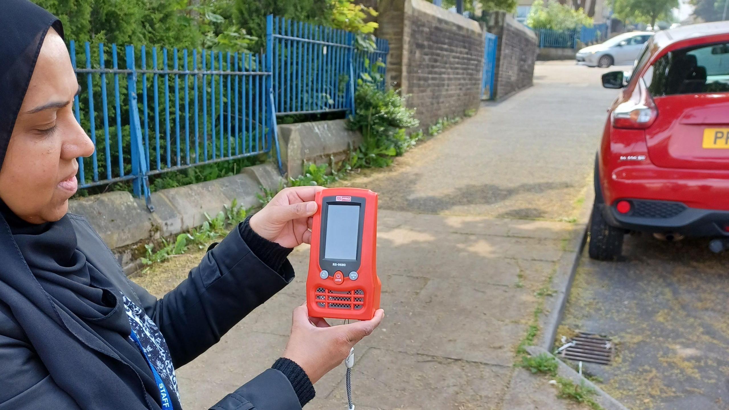 Woman using an air quality monitor next to a school in Bradford