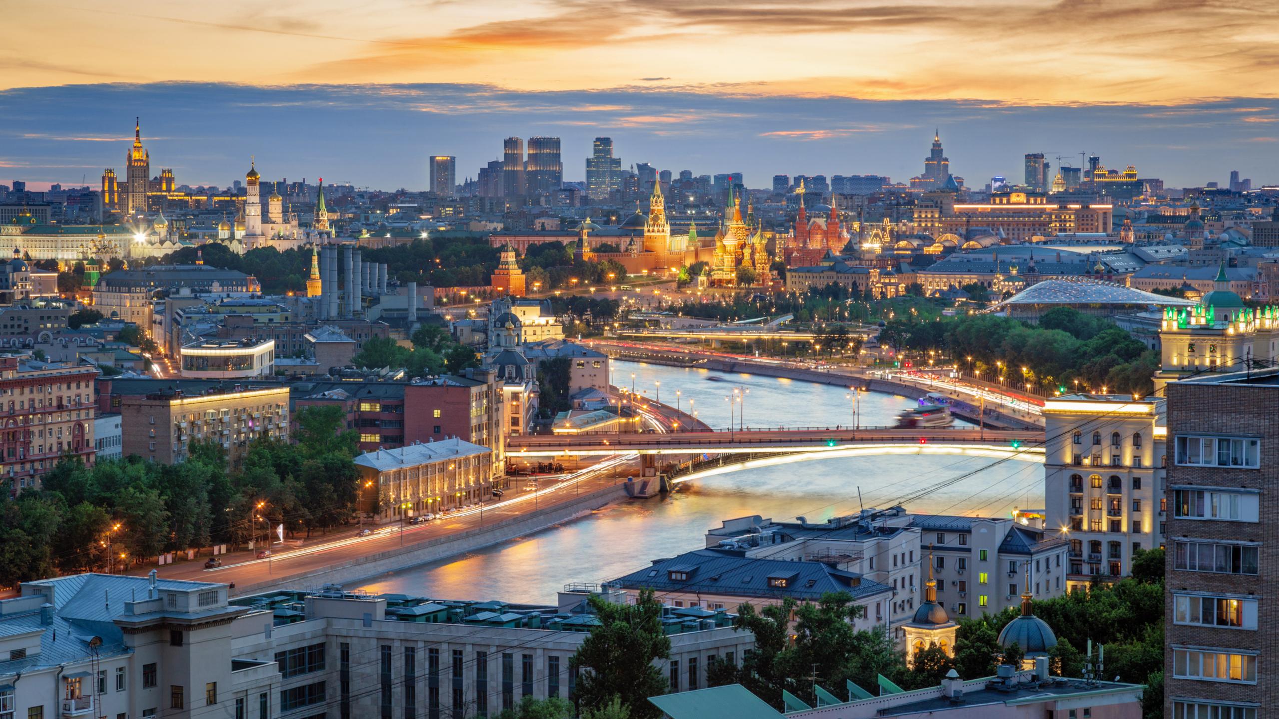 Closeup aerial view of the Moscow Kremlin destinations (Spasskaya Tower, St. Basil's Cathedral and Red Square) and modern residential buildings on the background after sunset in summer.