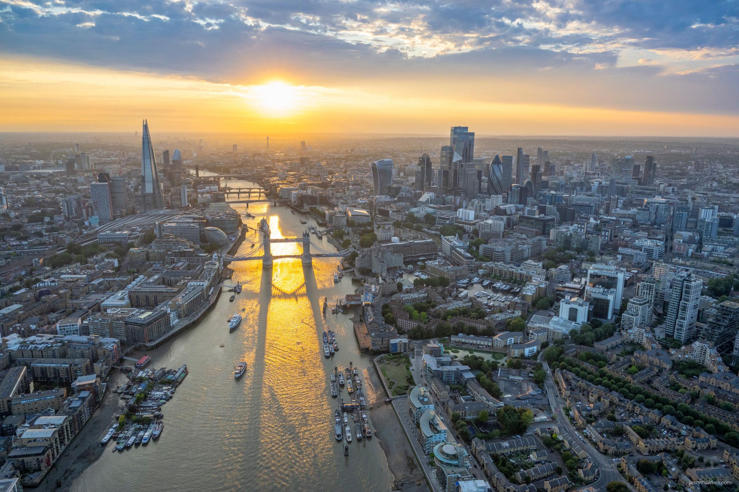 Sun sets over River Thames, showing Tower Bridge in foreground and Shard and City of London in background