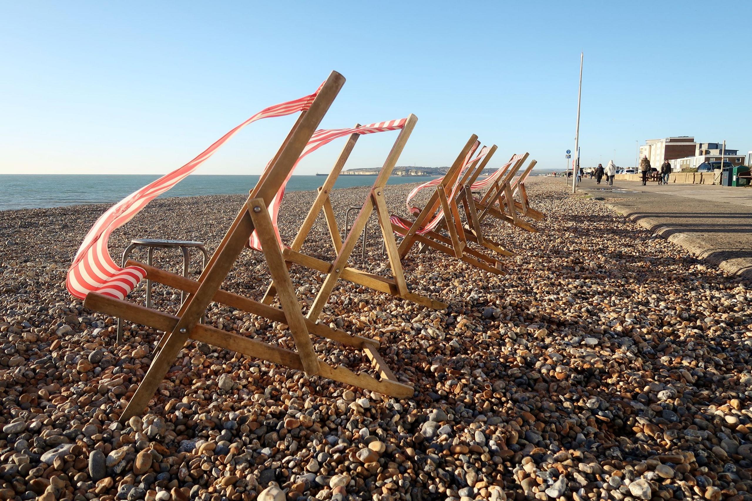 Deckchairs blowing in the wind on a stony beach