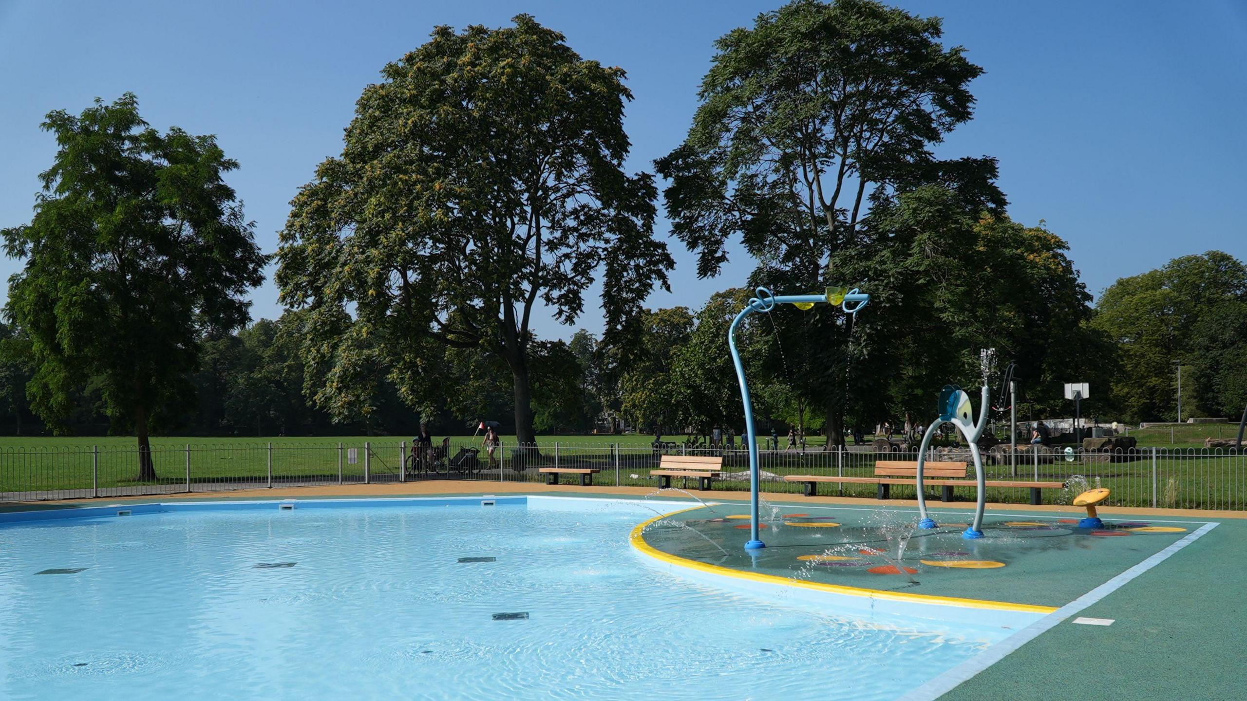 A splash park, with a large shallow area of water with a number of water play equipment